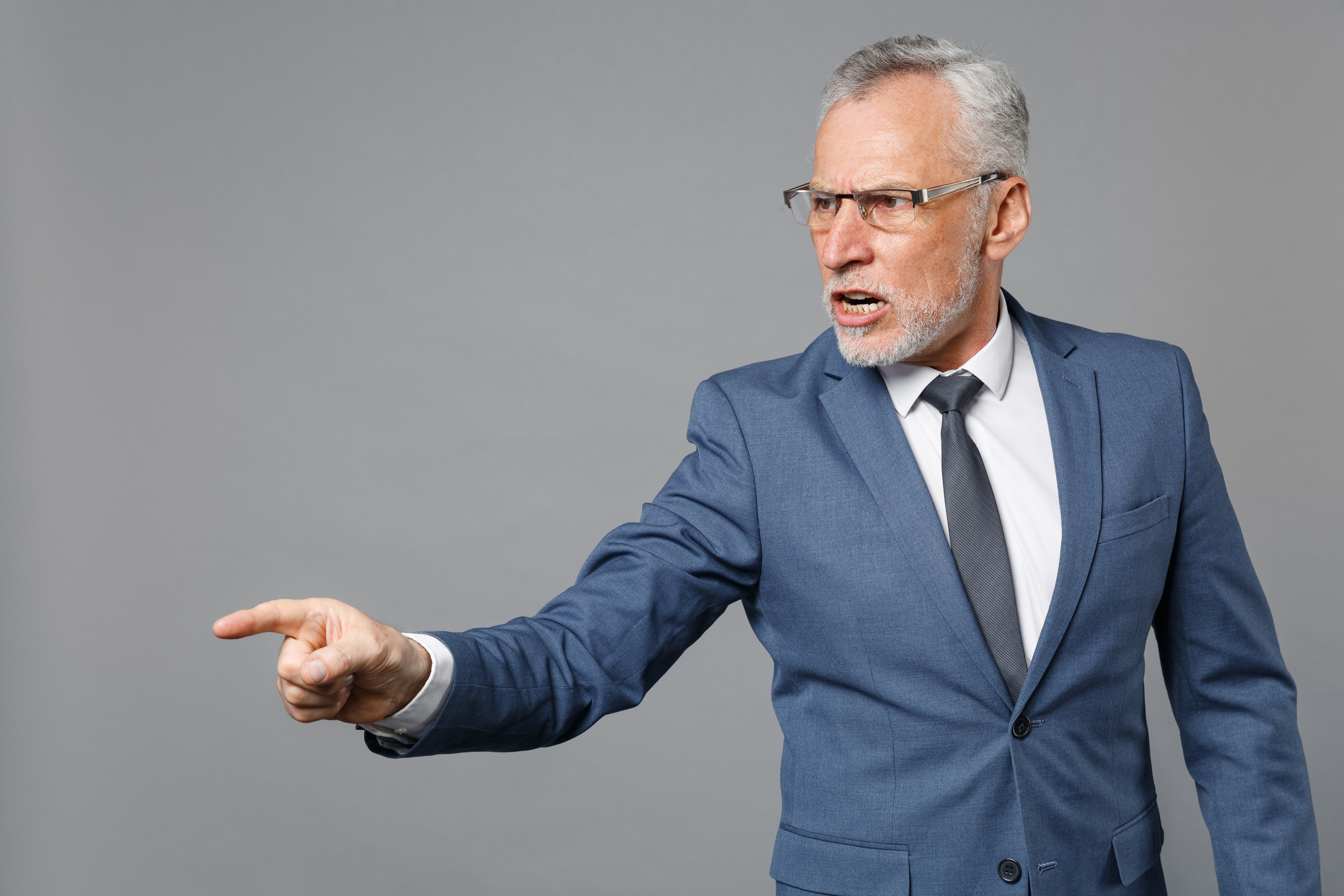 Angry elderly gray-haired bearded business man. | Source: Shutterstock