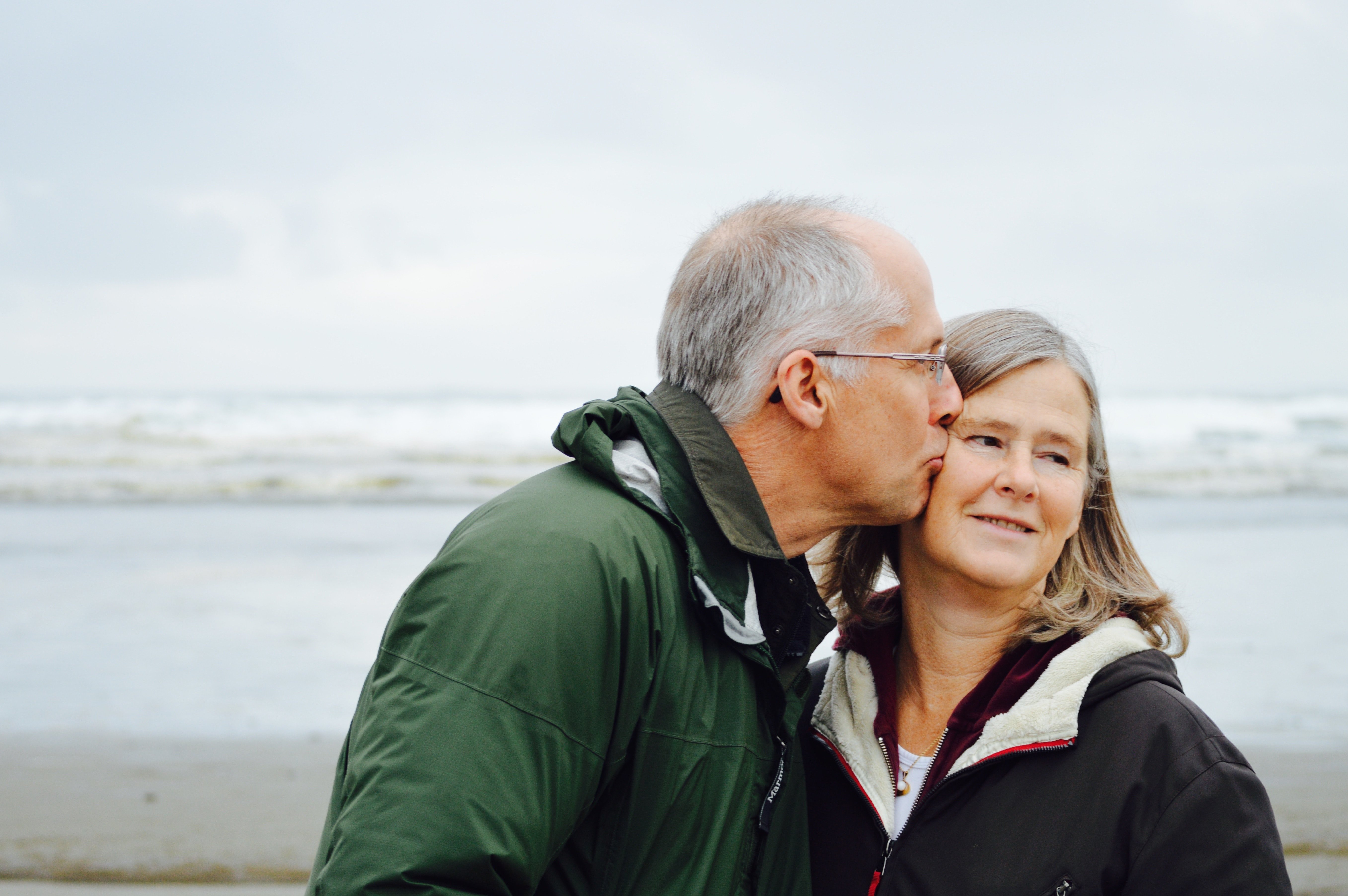 An elderly man kissing an elderly woman on her cheek. | Source: Unsplash