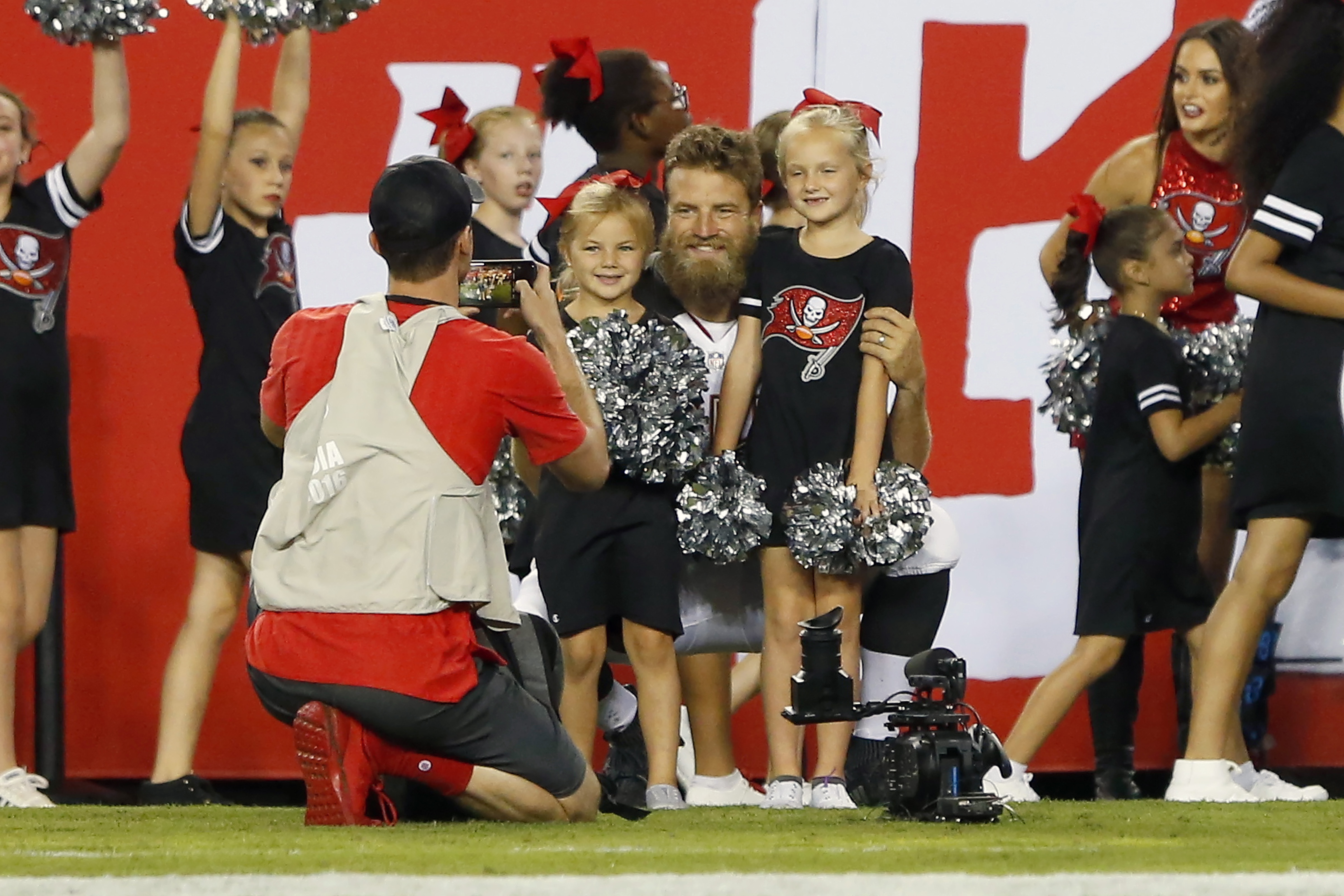 Ryan Fitzpatrick poses for a photographer with two of his girls at the start of half-time during a preseason game between on August 24, 2018, in Tampa, Florida | Source: Getty Images