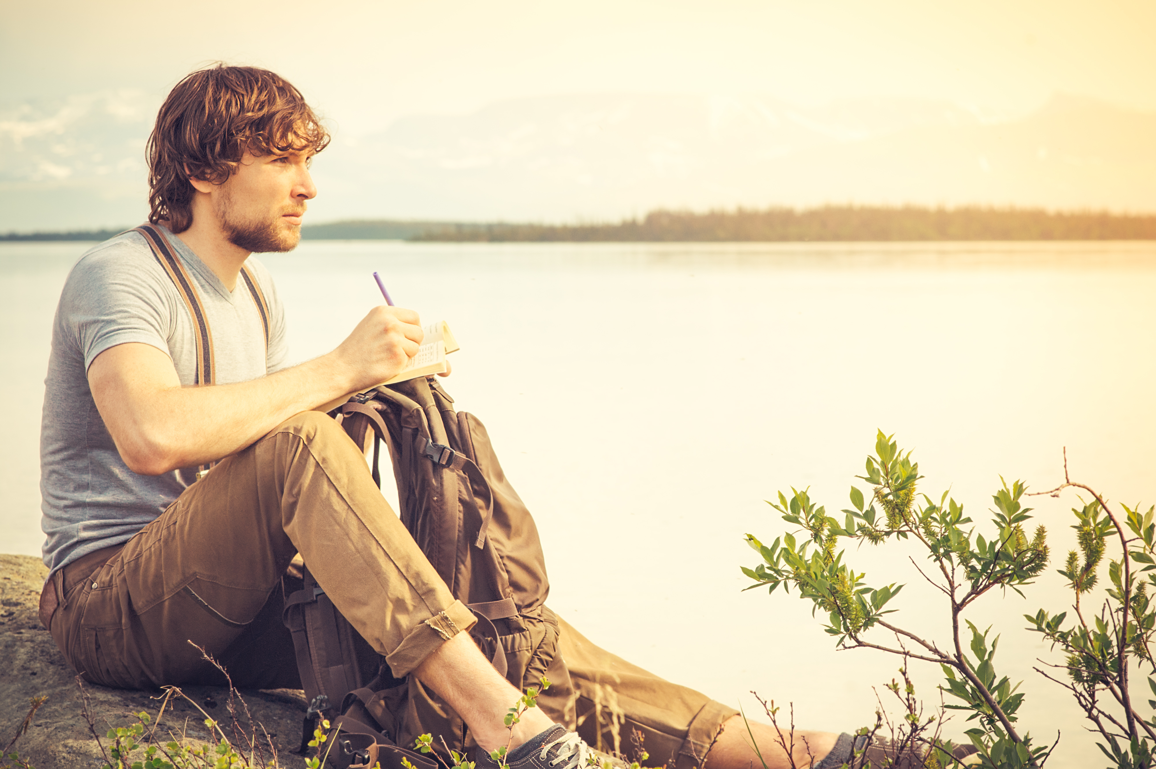 Young Man reading book outdoor with lake on background | Source: Getty Images