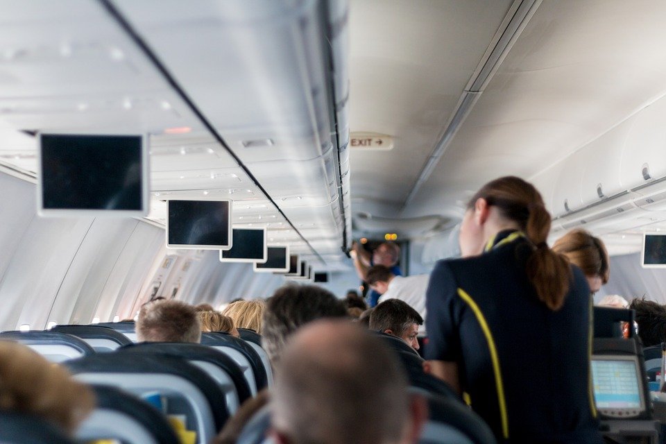 Pasajeros en los asientos de un avión mientas la azafata camina por el pasillo. | Foto: Pixabay