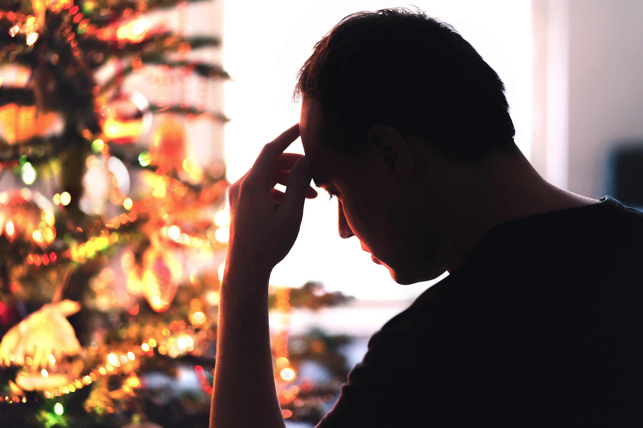 Upset man sitting in front of a Christmas tree | Source: Getty Images