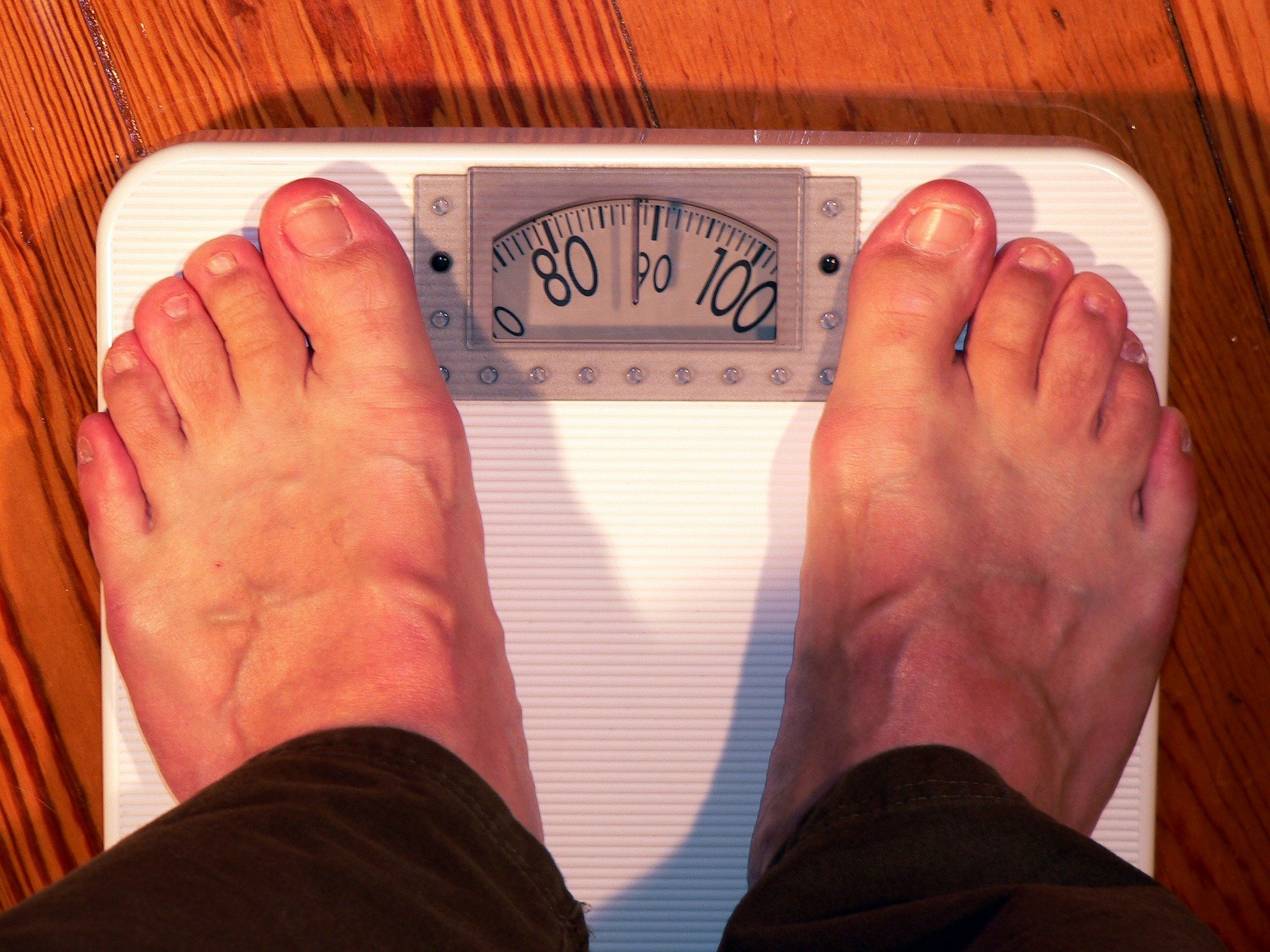 A man on a scale checking out his weight | Photo: Pixabay