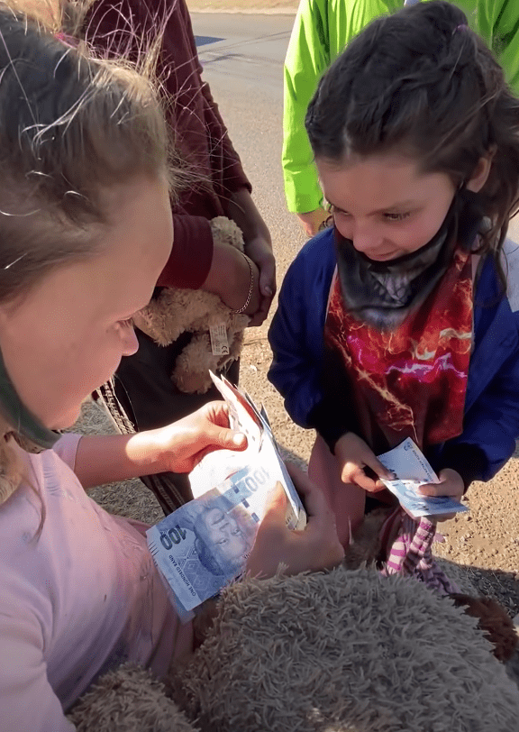 A girl counts the money given to her by a kind stranger | Photo: youtube.com/BI Phakathi