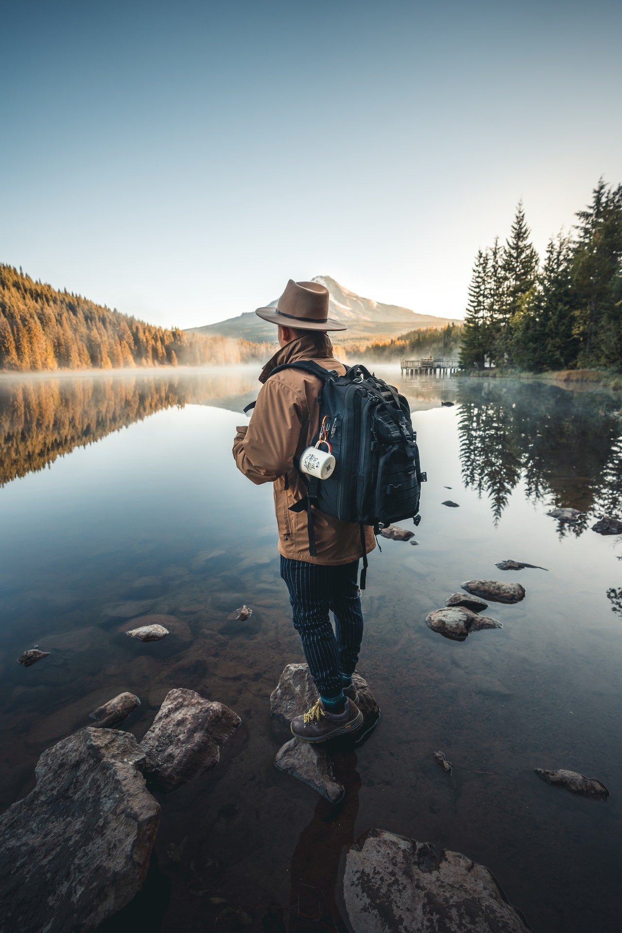 Photo of a man in a brown jacket standing on a rock | Photo: Pexels