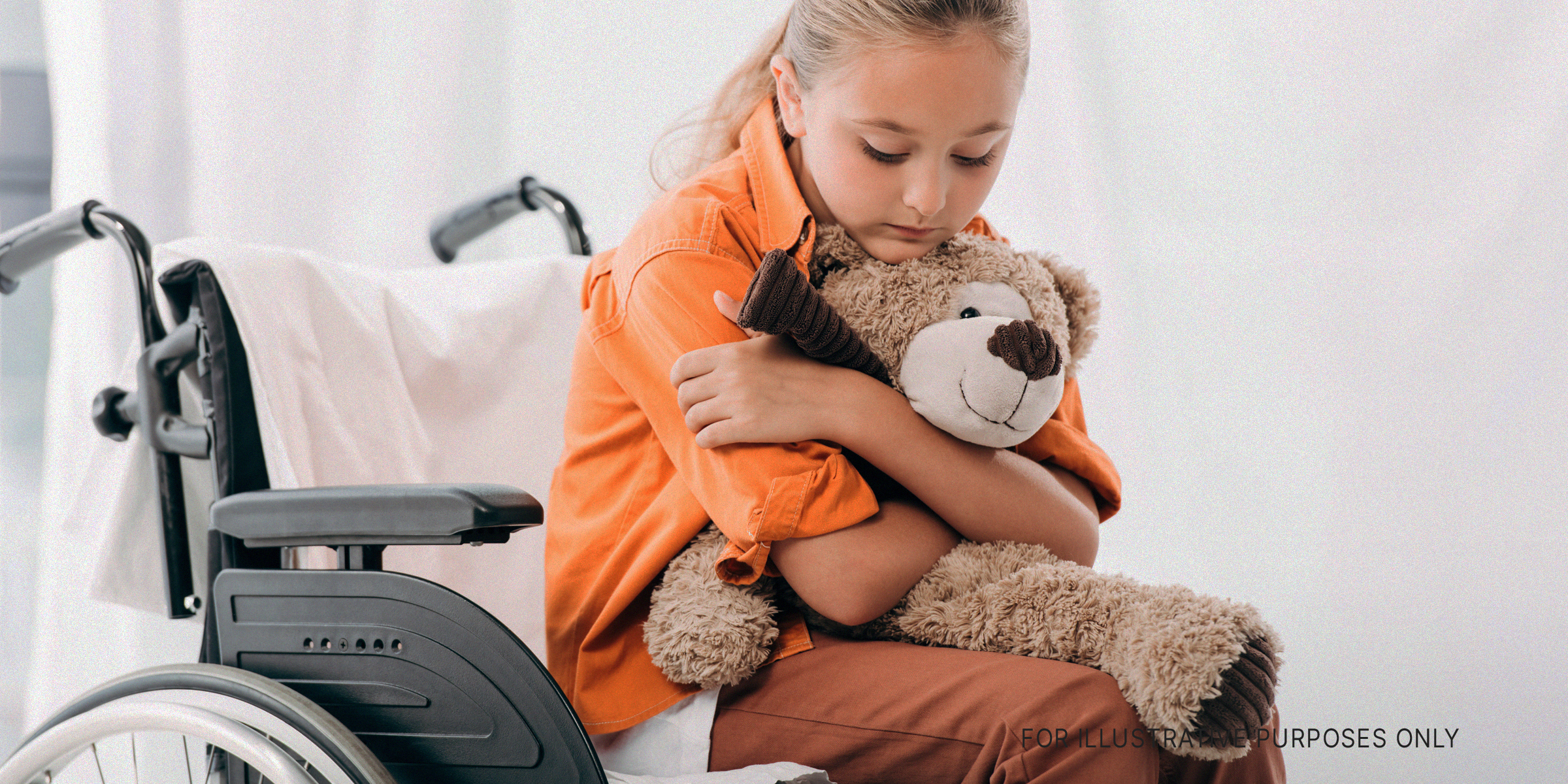 Child sitting on a wheelchair with a teddy bear | Source: Shutterstock