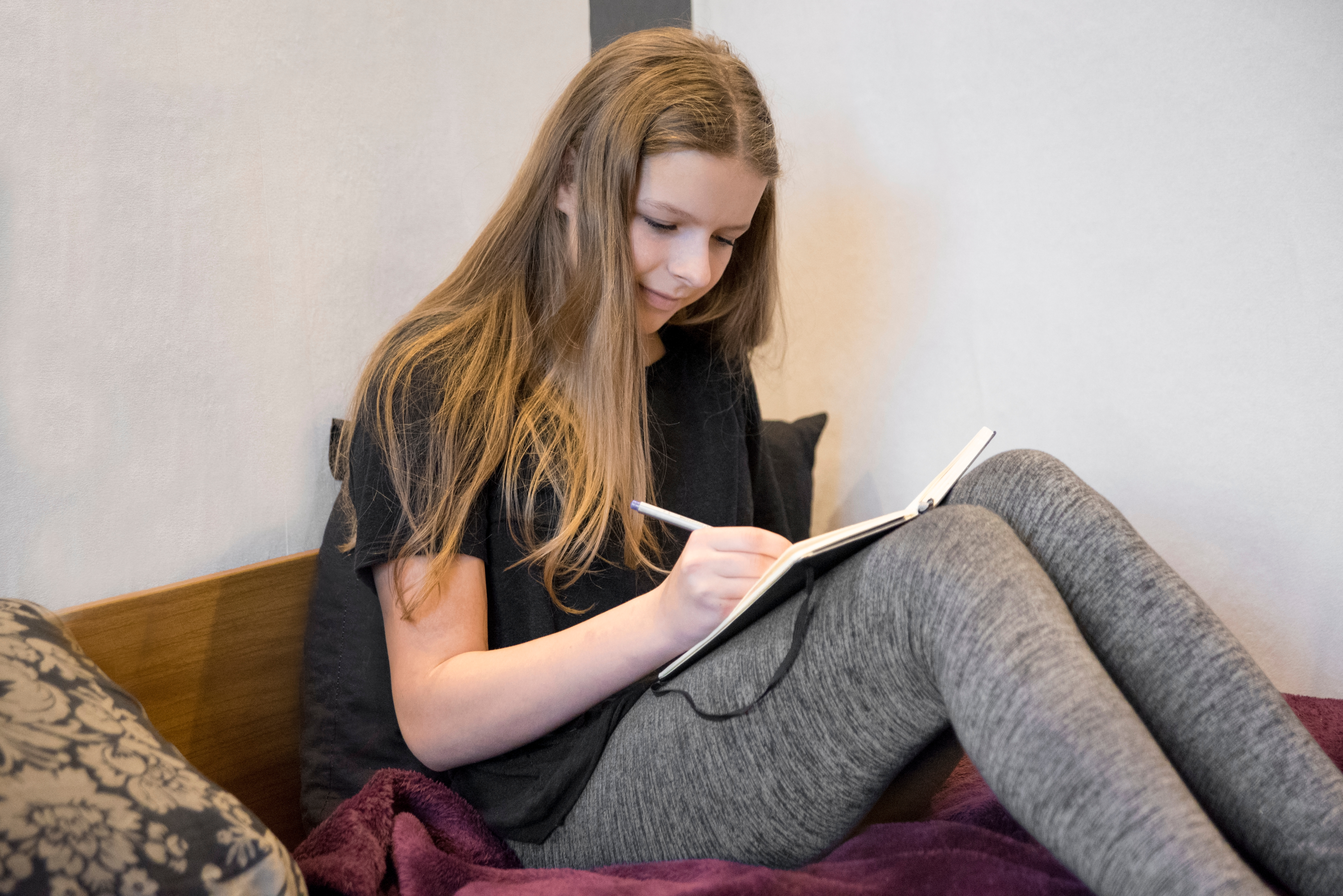 Girl sitting on a bed writing on her journal | Source: Shutterstock
