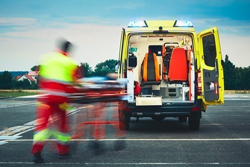 Paramedic is pulling stretcher with the patient to the ambulance car. | Source: Shutterstock