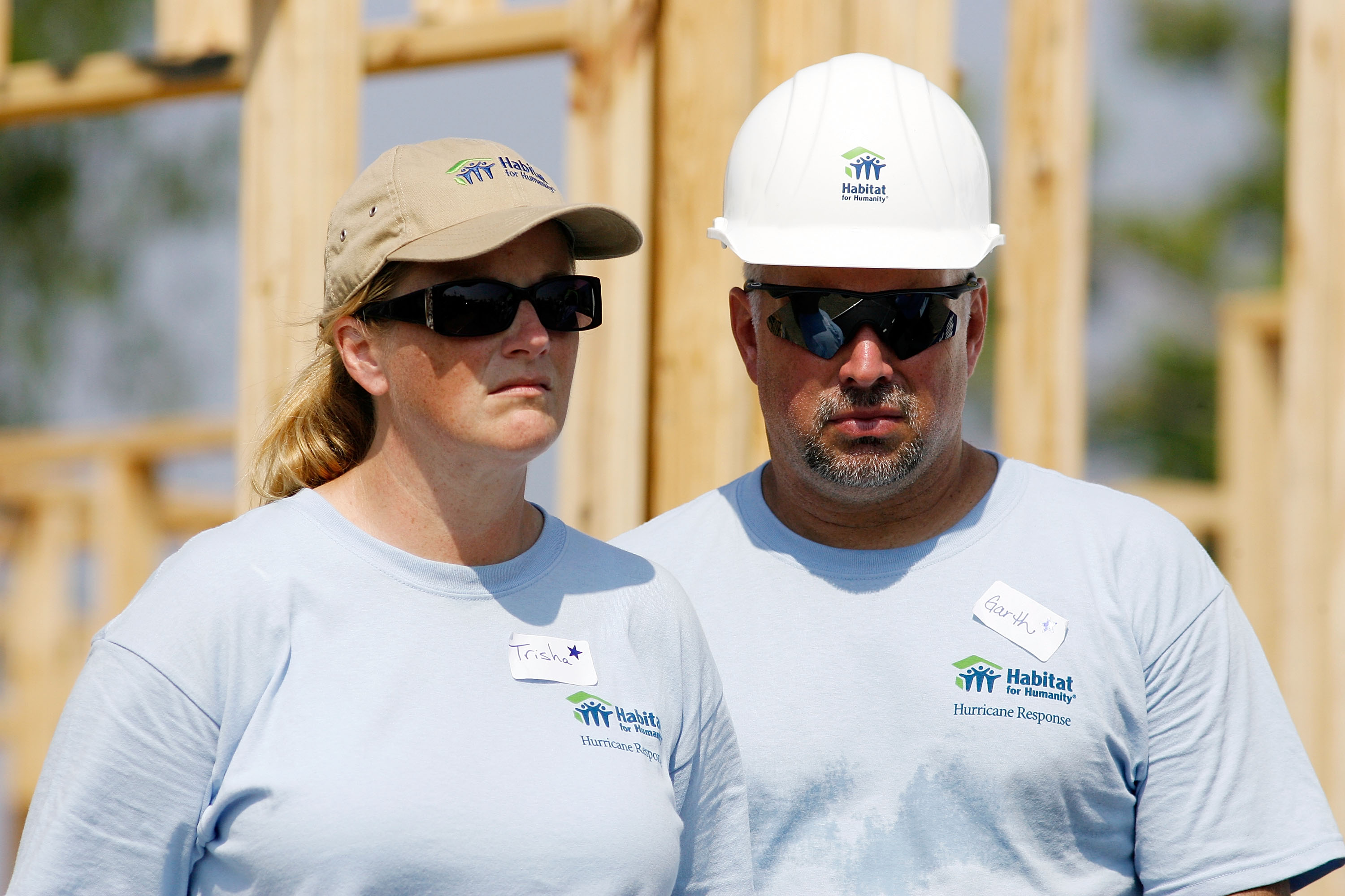 Trisha Yearwood and Garth Brooks listen to former U.S. President Jimmy Carter speak after raising the wall on the 1,000th and 1,001st homes to be built by Habitat for Humanity on the Gulf Coast in Violet, Louisiana, on May 21, 2007. | Source: Getty Images