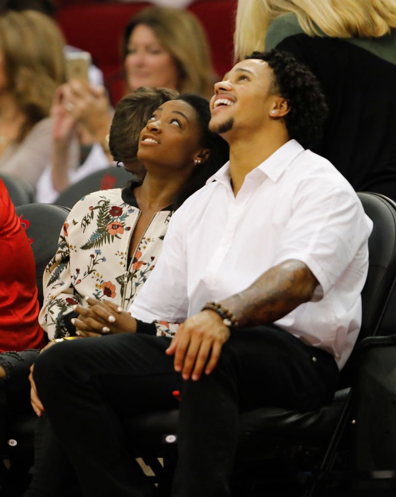 imone Biles and Stacey Ervin watch the game between the Houston Rockets and the Utah Jazz ,2017| Photo: Getty Images