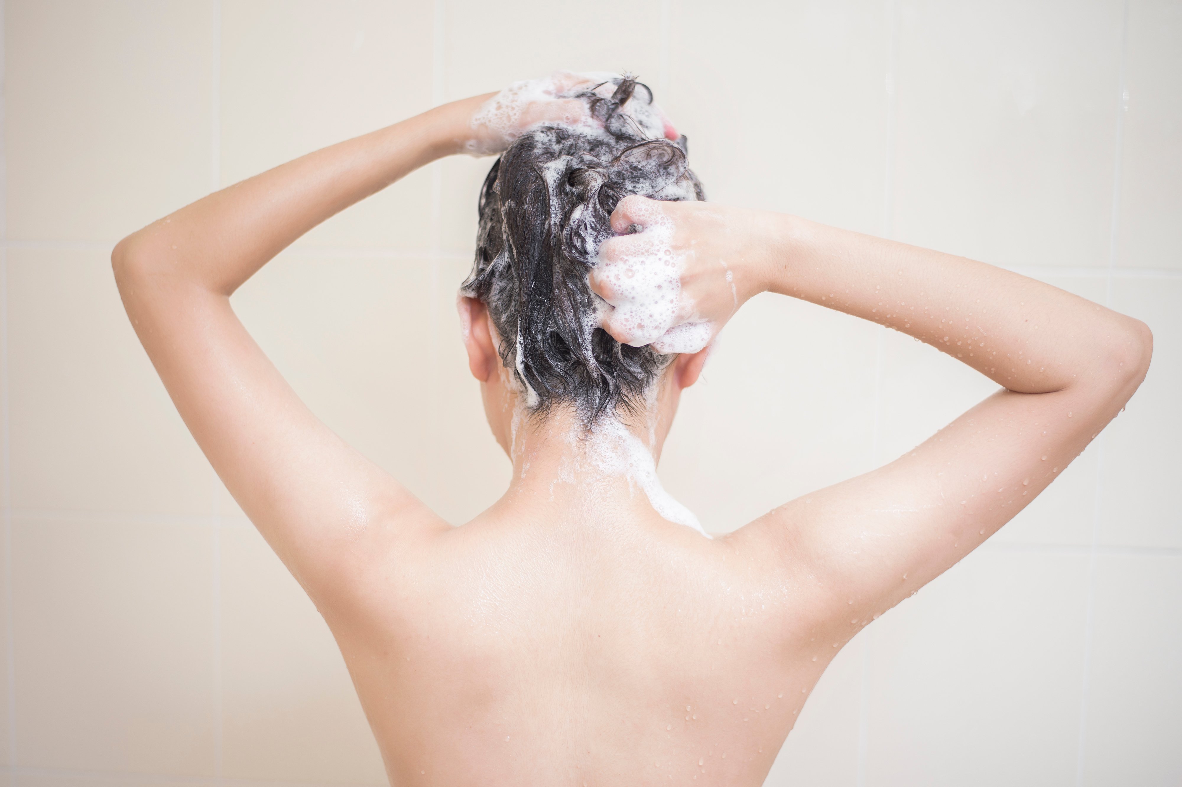 Mujer aplicando champú en su cabello. | Foto: Shutterstock