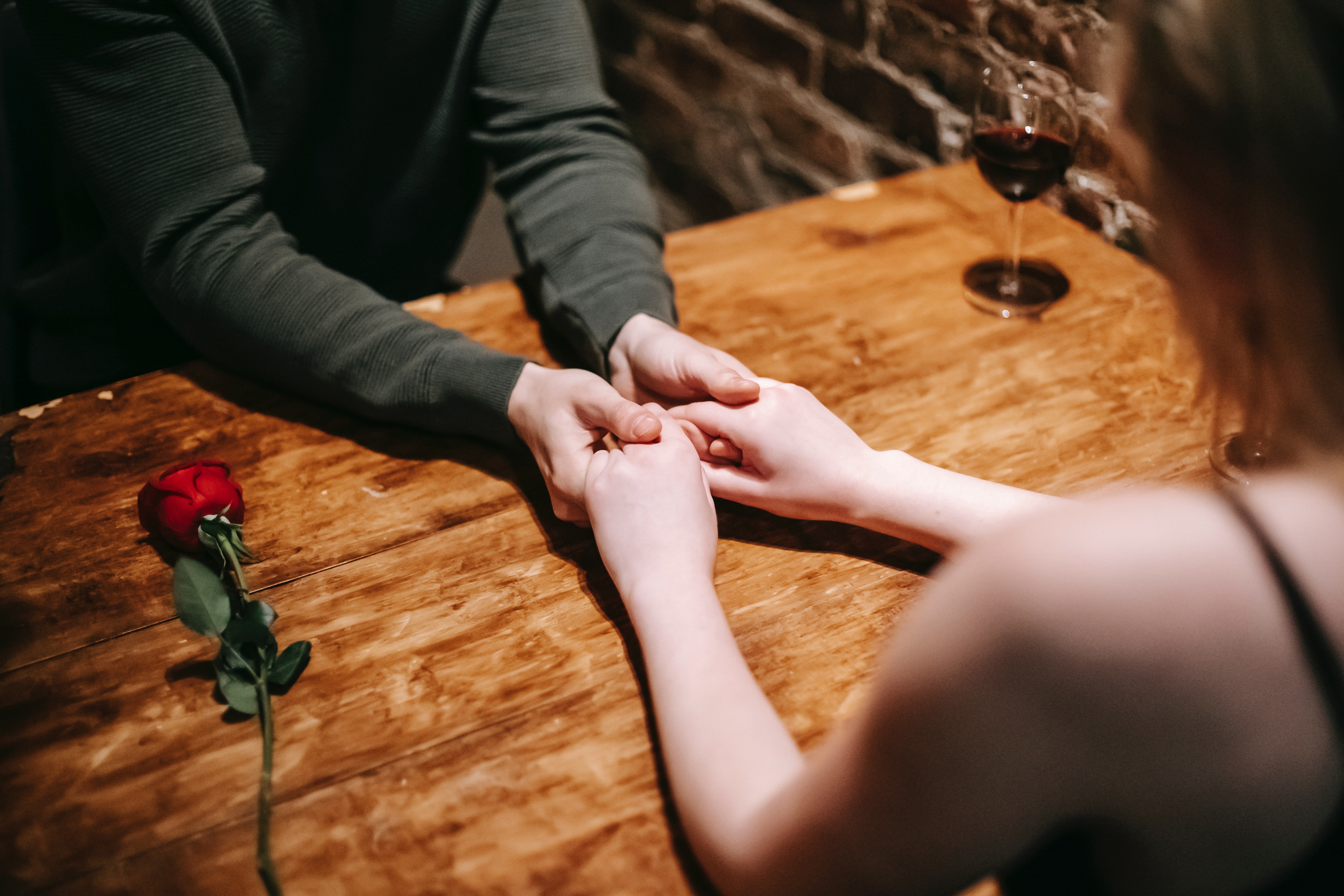 Ein Paar hält am Tisch Hände | Quelle: Pexels