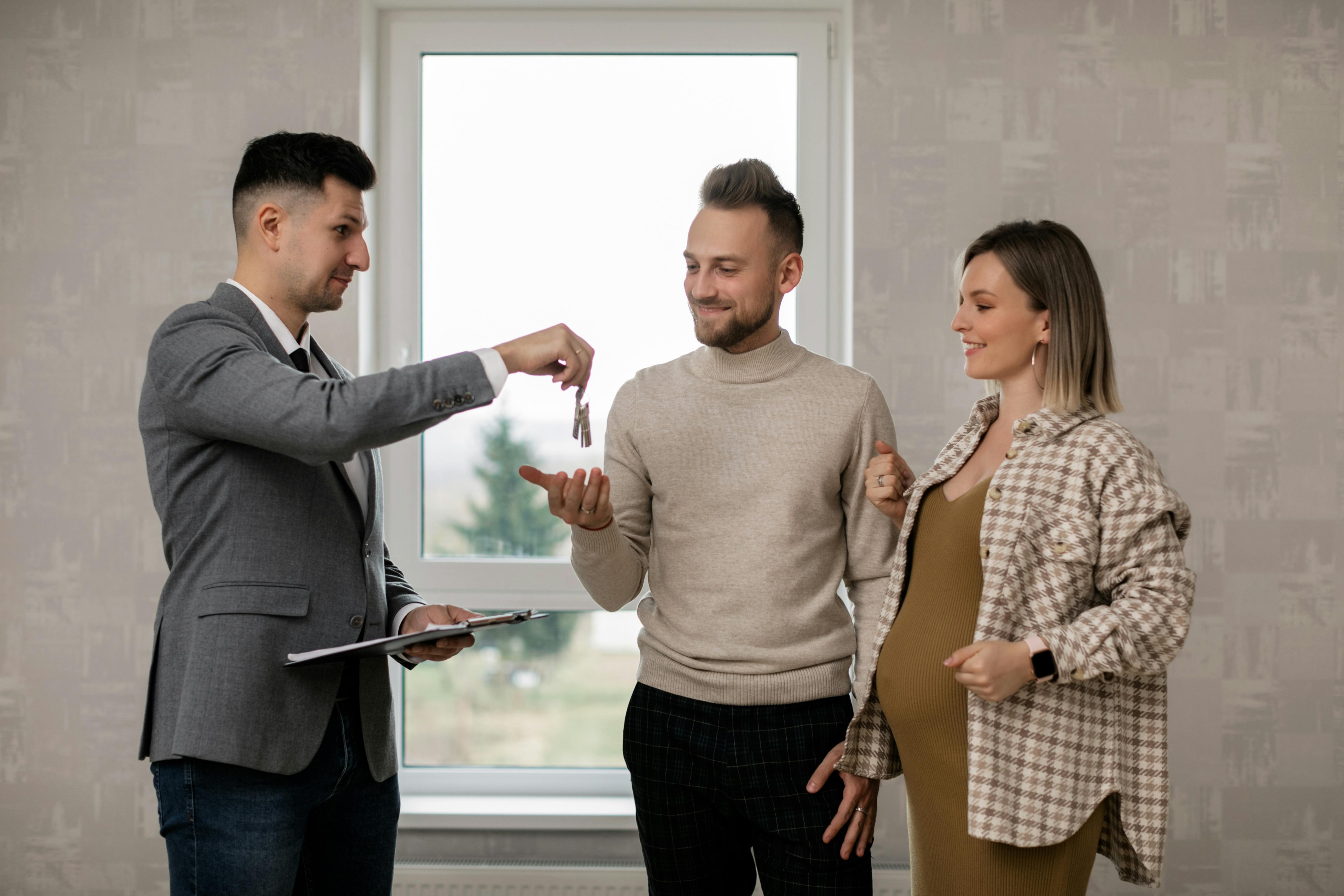 A real estate agent handing the key to new homeowners | Source: Pexels