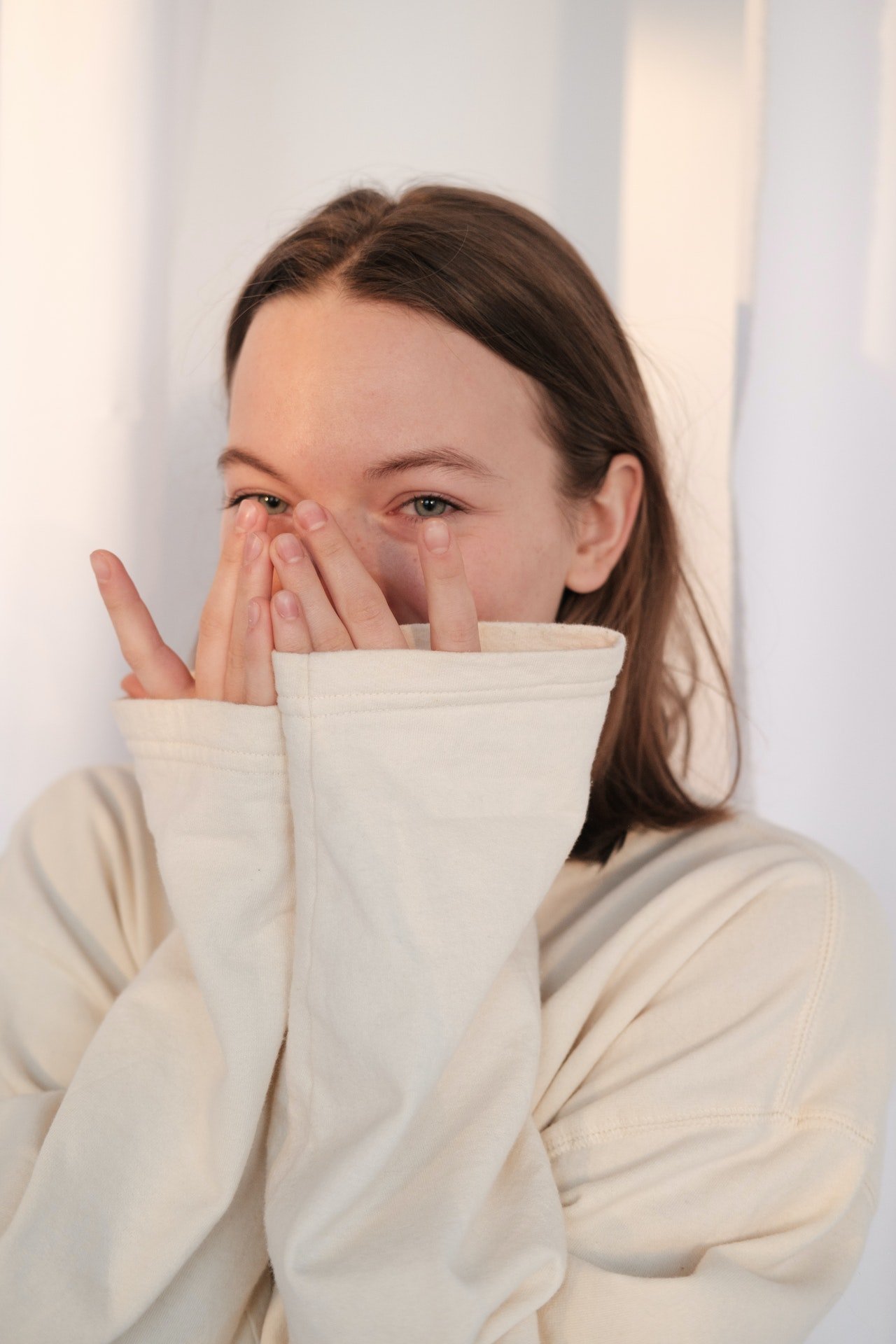 Una mujer emocionada con los ojos llorosos cubriendo su rostro con sus manos. | Foto: Pexels