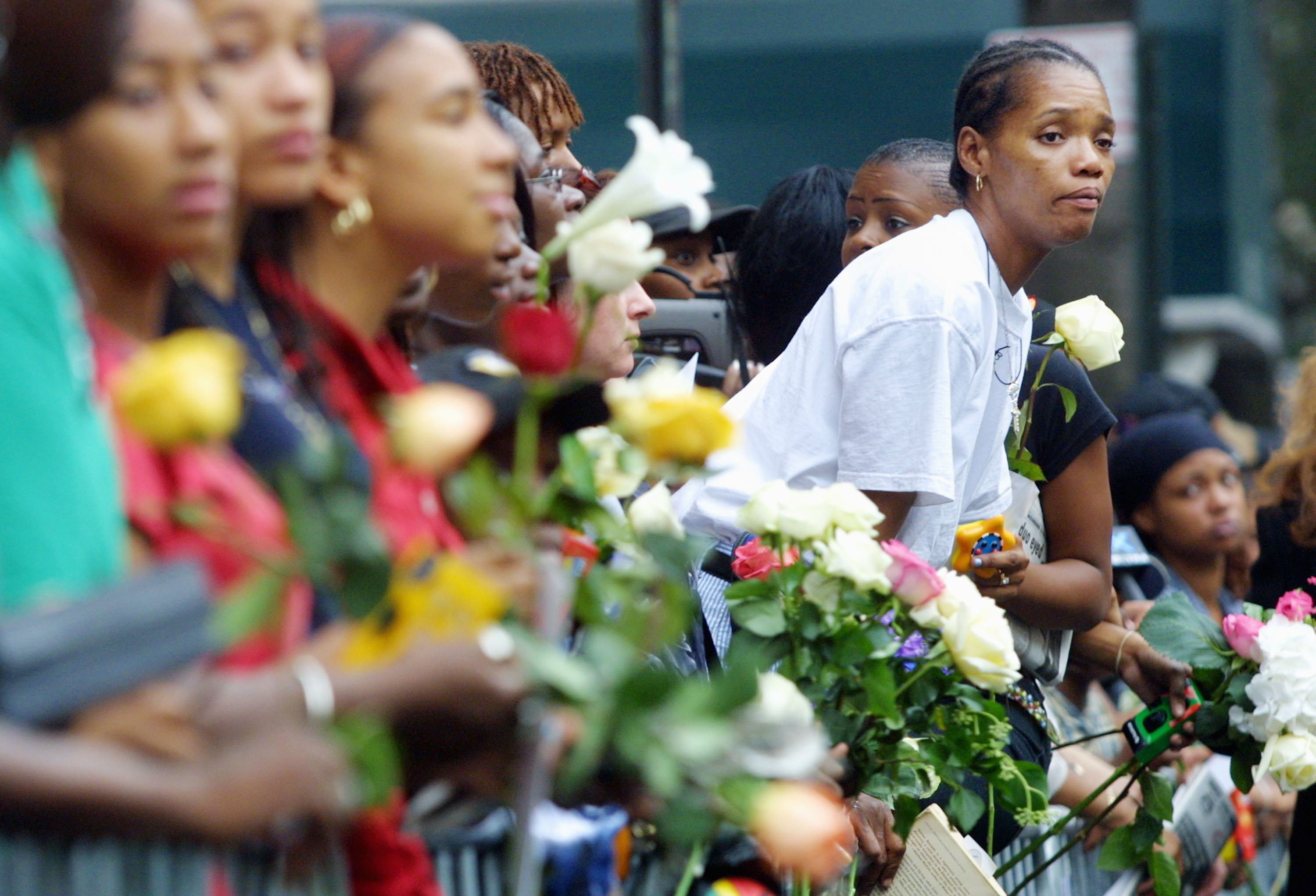 Fans line the streets of New York holding flowers as they watch the procession carrying Aaliyah's casket on August 31, 2001 | Source: Getty Images