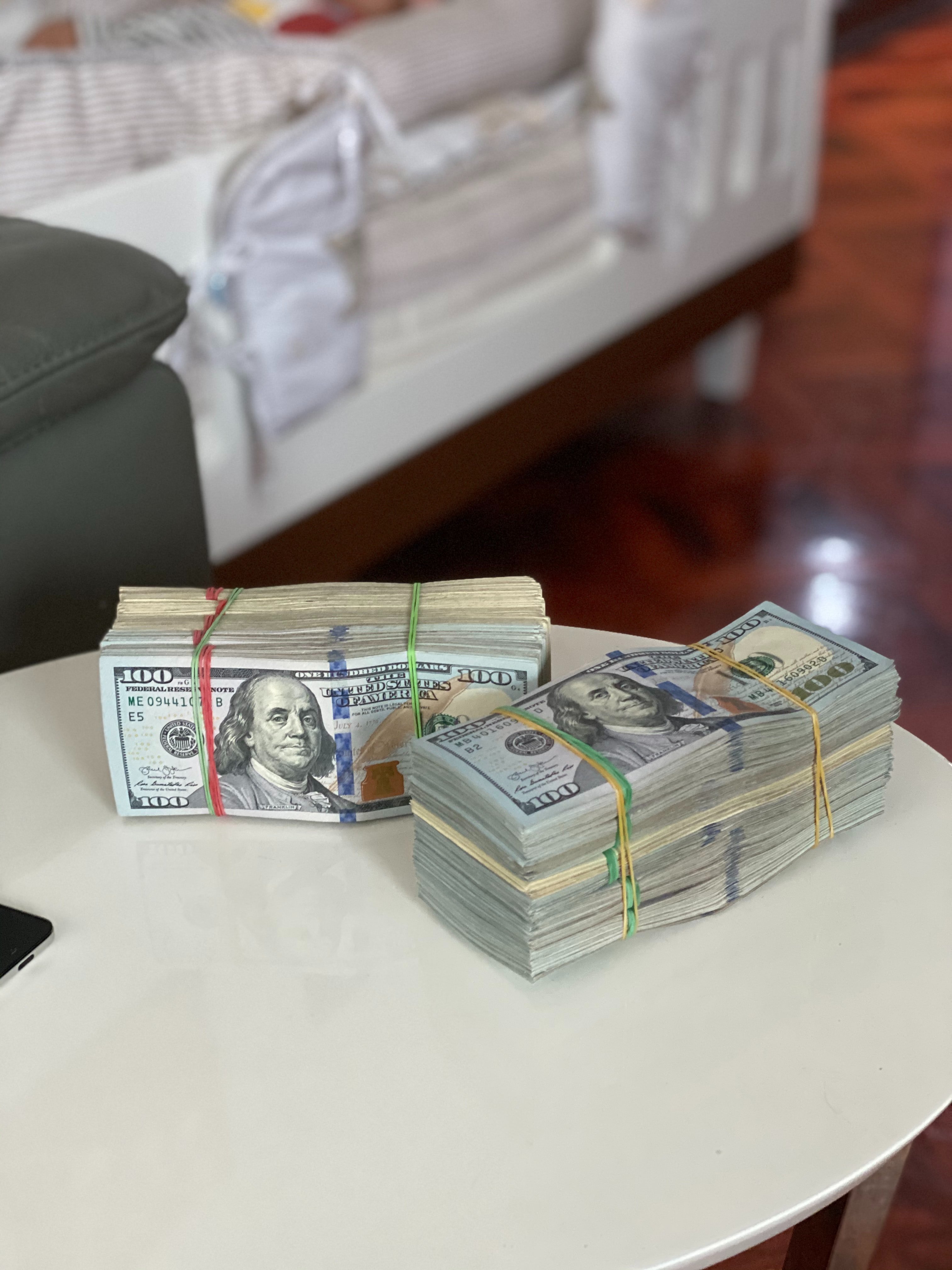 Dos grandes fajos de billetes de cien dólares sobre una mesa. | Foto: Pexels