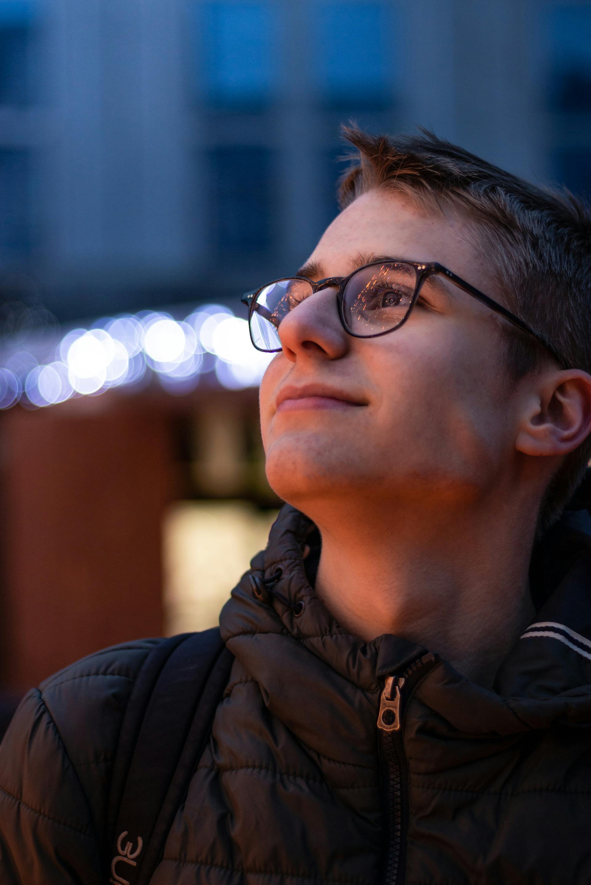 A smiling teenage boy wearing a jacket and eyeglasses | Source: Pexels