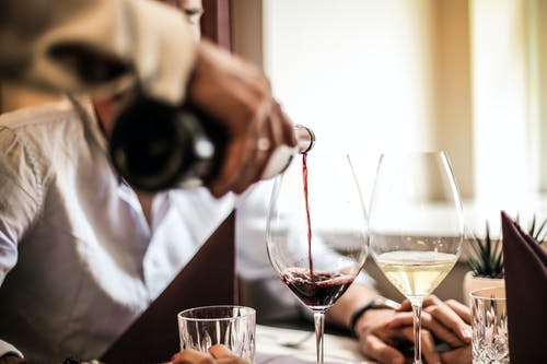 A waiter pouring wine into wine cups. | Photo: Pexel