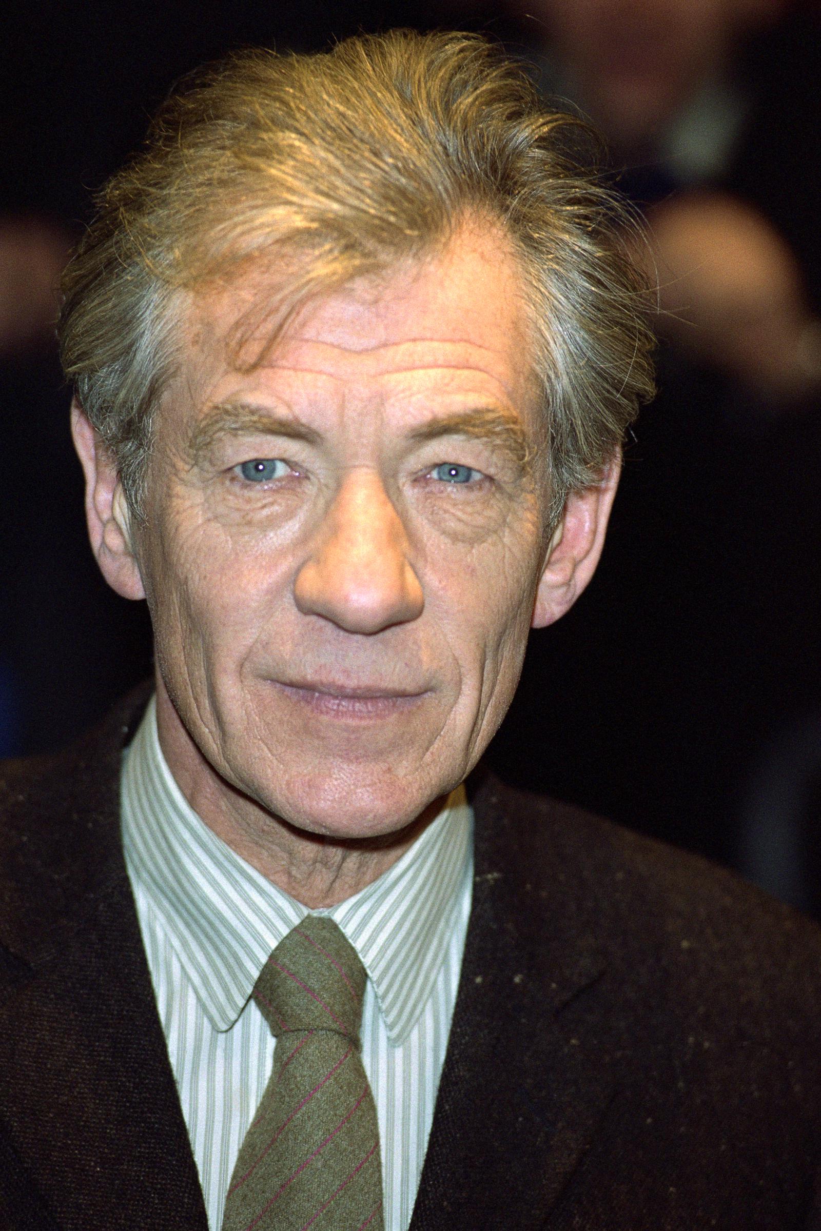 Ian McKellen in 2001, wearing a dark jacket over a striped dress shirt and patterned tie, his calm expression and piercing eyes giving him a distinguished, thoughtful look.