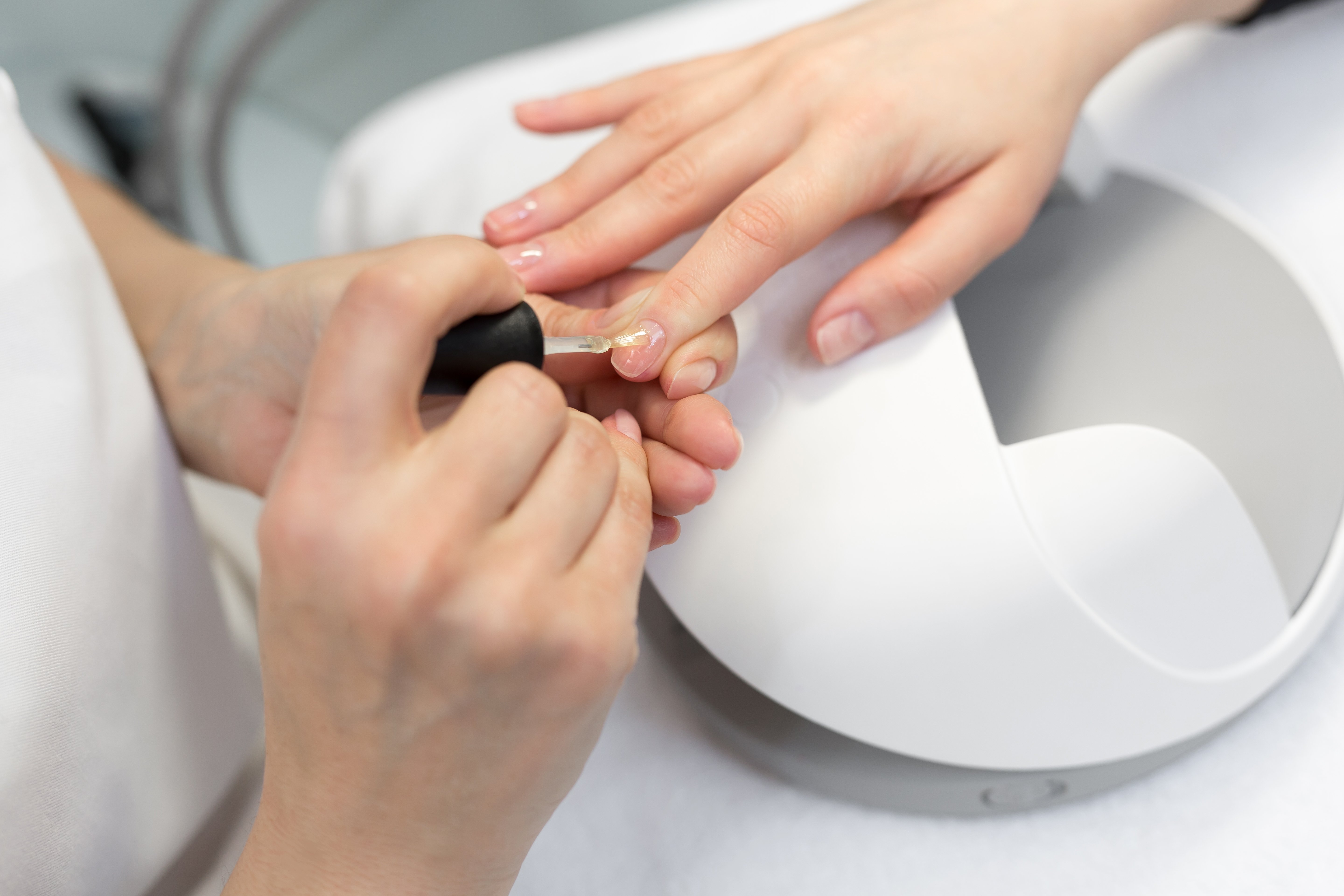 A nail technician applying nail polish to a woman's fingers. | Source: Shutterstock