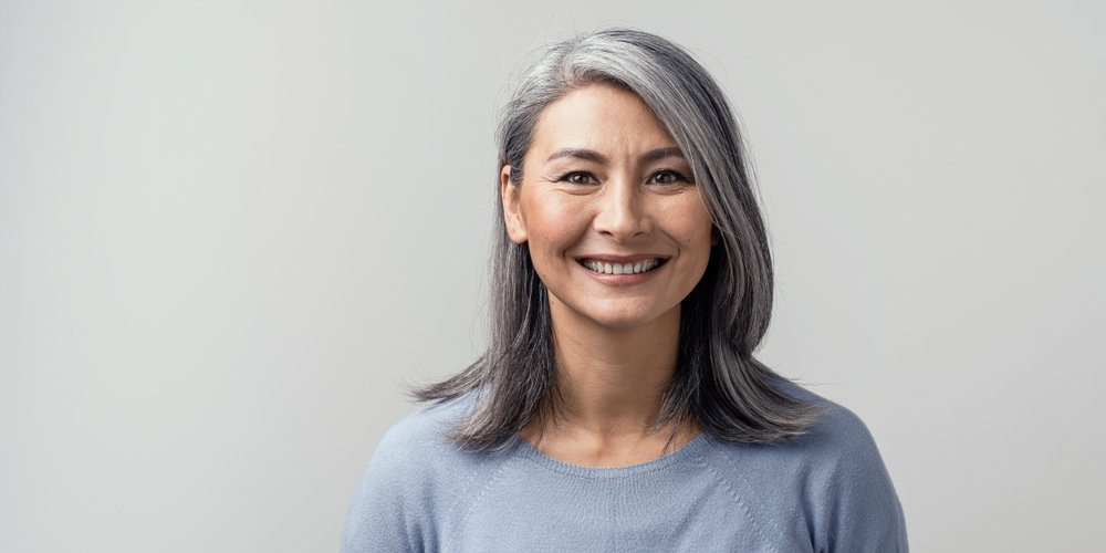 Schöne, reife asiatische Frau lächelt im Studio. I Quelle: Shutterstock