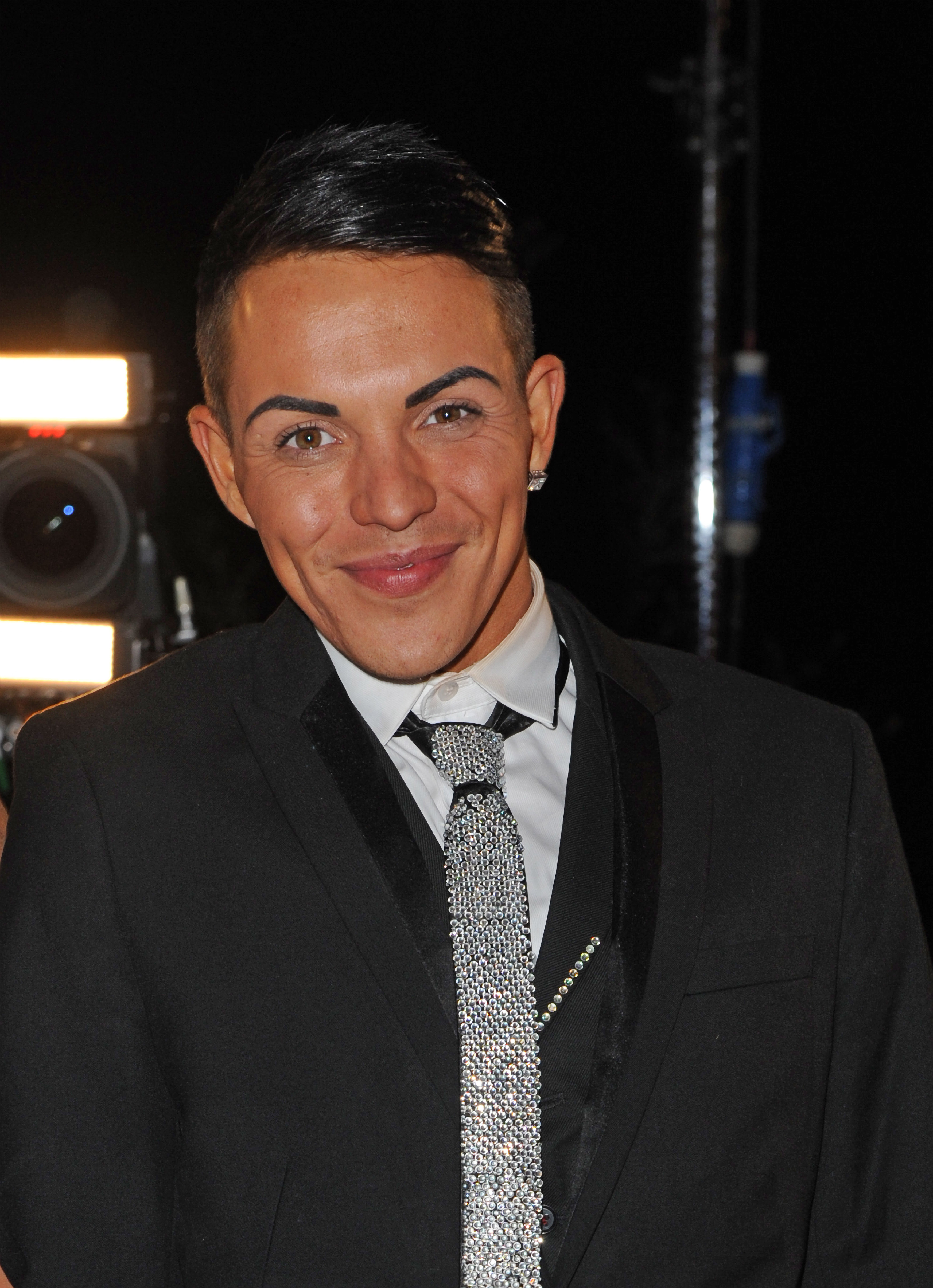 Bobby Norris poses backstage at the "Towie" live episode in December 2012 — fresh-faced and bright-eyed, his dark hair swept back, wearing a black blazer and a silver sequinned tie that caught every studio light.