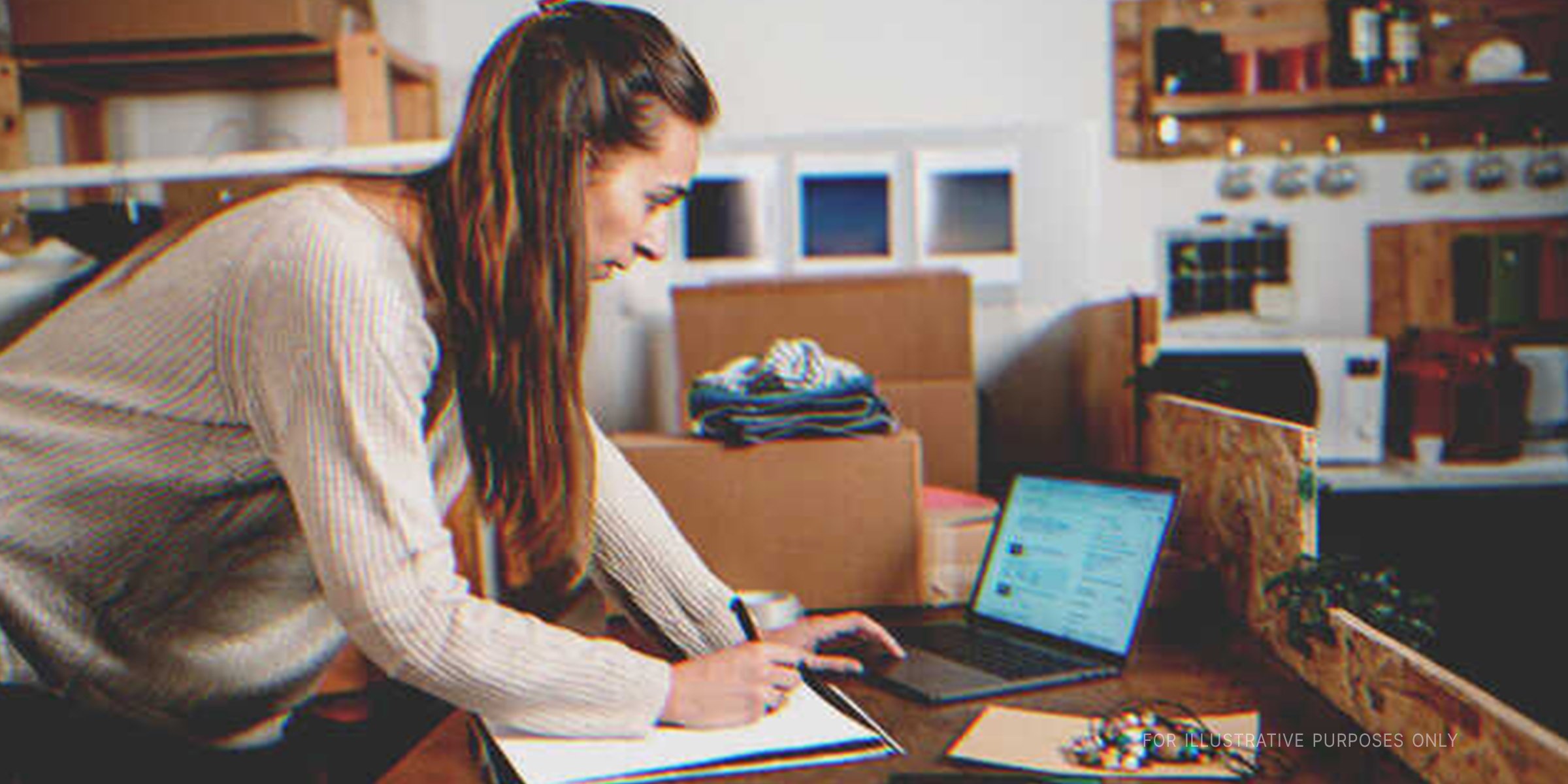 Woman writing something down and using her computer. | Source: Getty Images