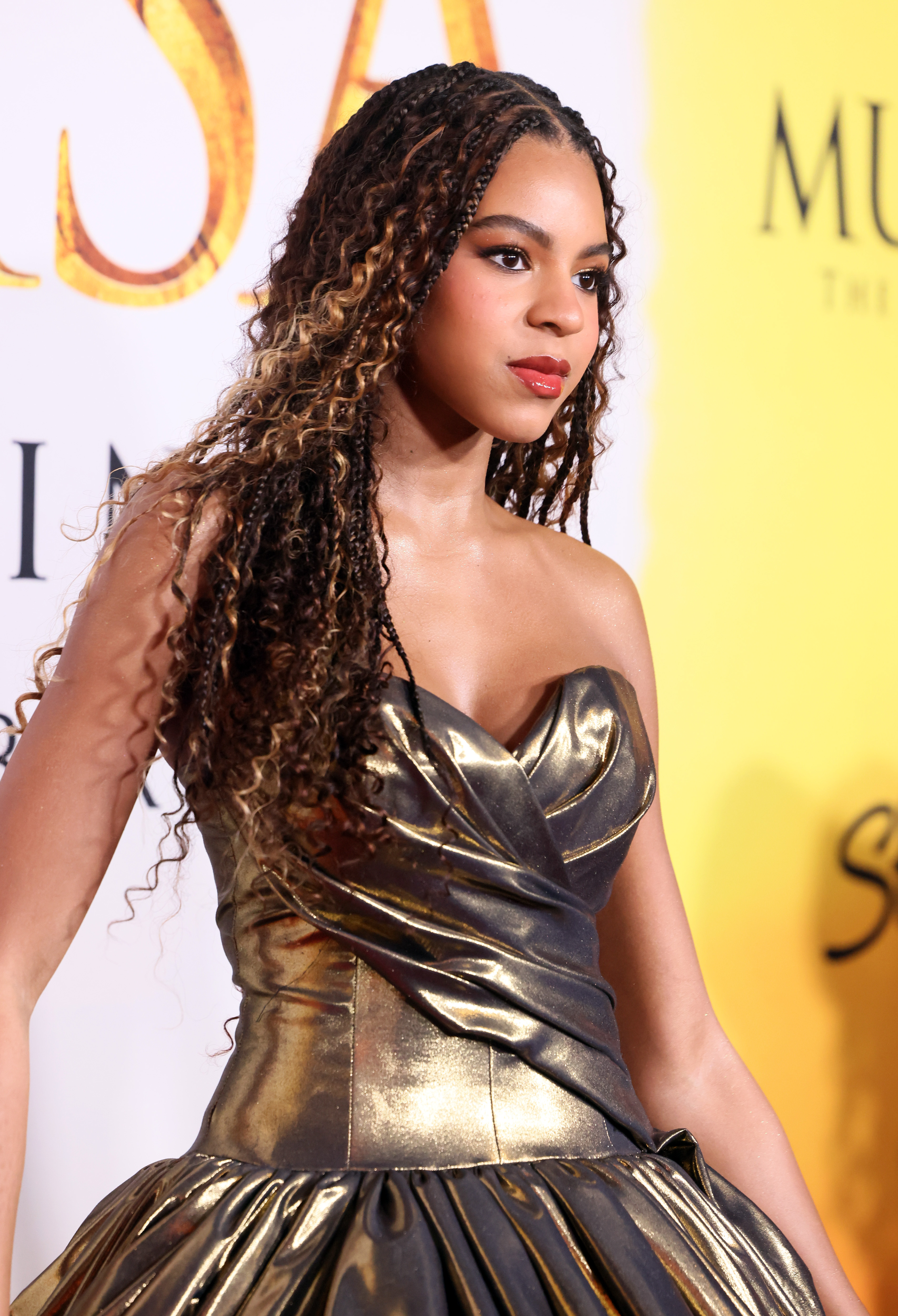 Blue Ivy Carter, 12, wore her long, coily braids with honey-blonde highlights down over her shoulders, along with a gold gown with a strapless sweetheart neckline, while attending the world premiere of Disney's "Mufasa: The Lion King" at the Dolby Theatre in Hollywood, California, on December 9, 2024.