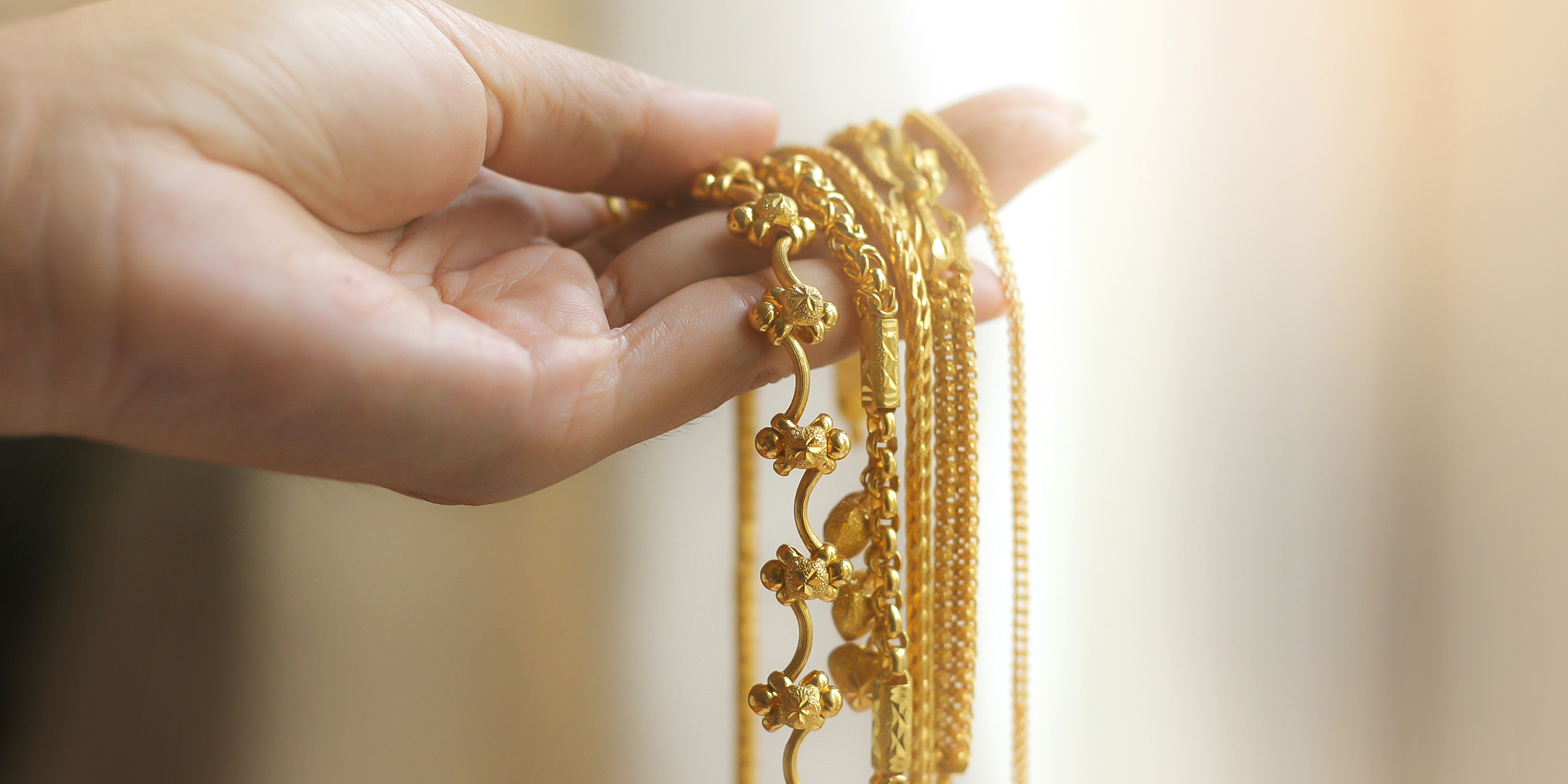 A woman's hand holding gold jewelry | Source: Shutterstock