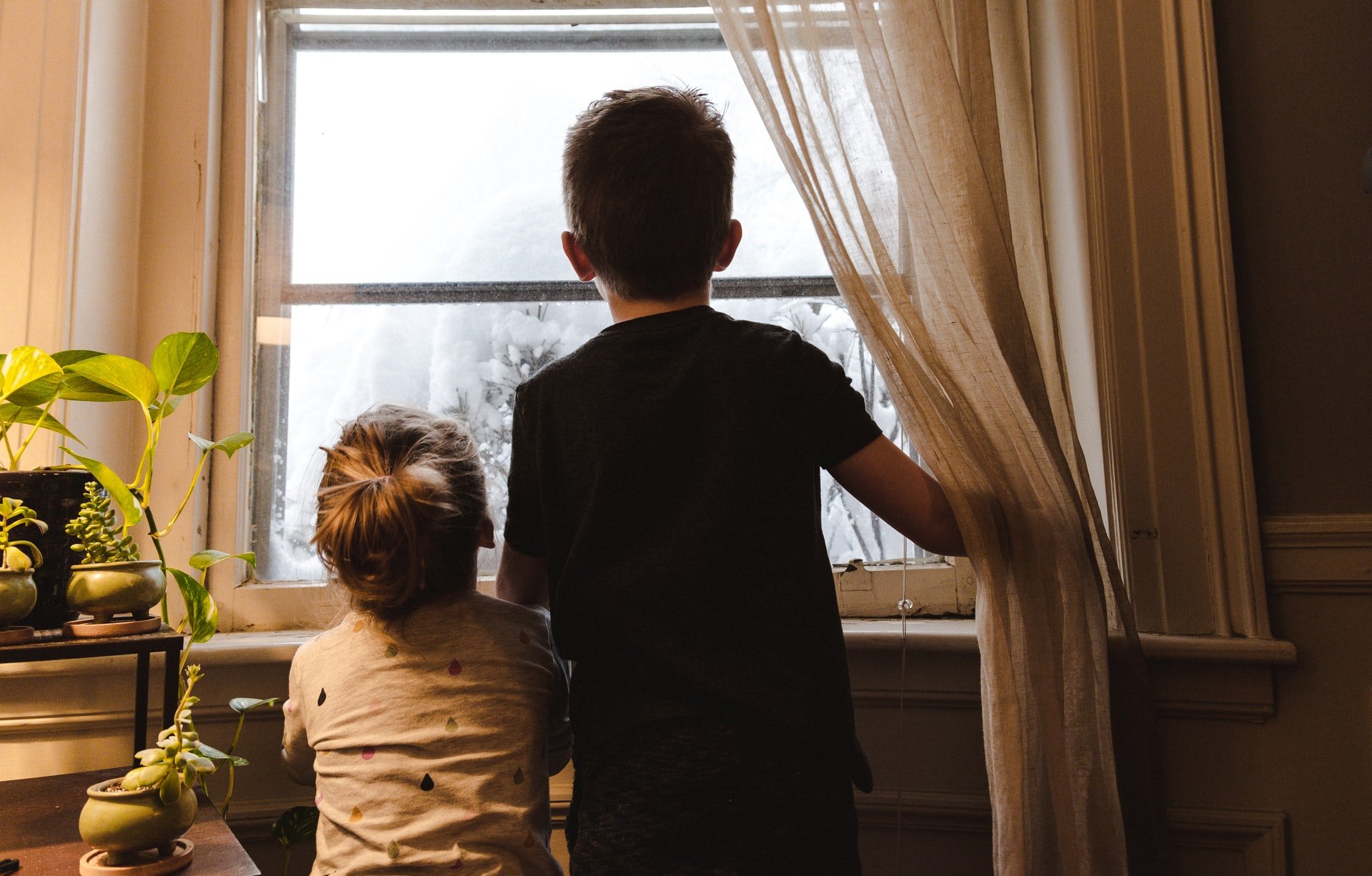 A little girl and young boy looking through the window | Source: Unsplash