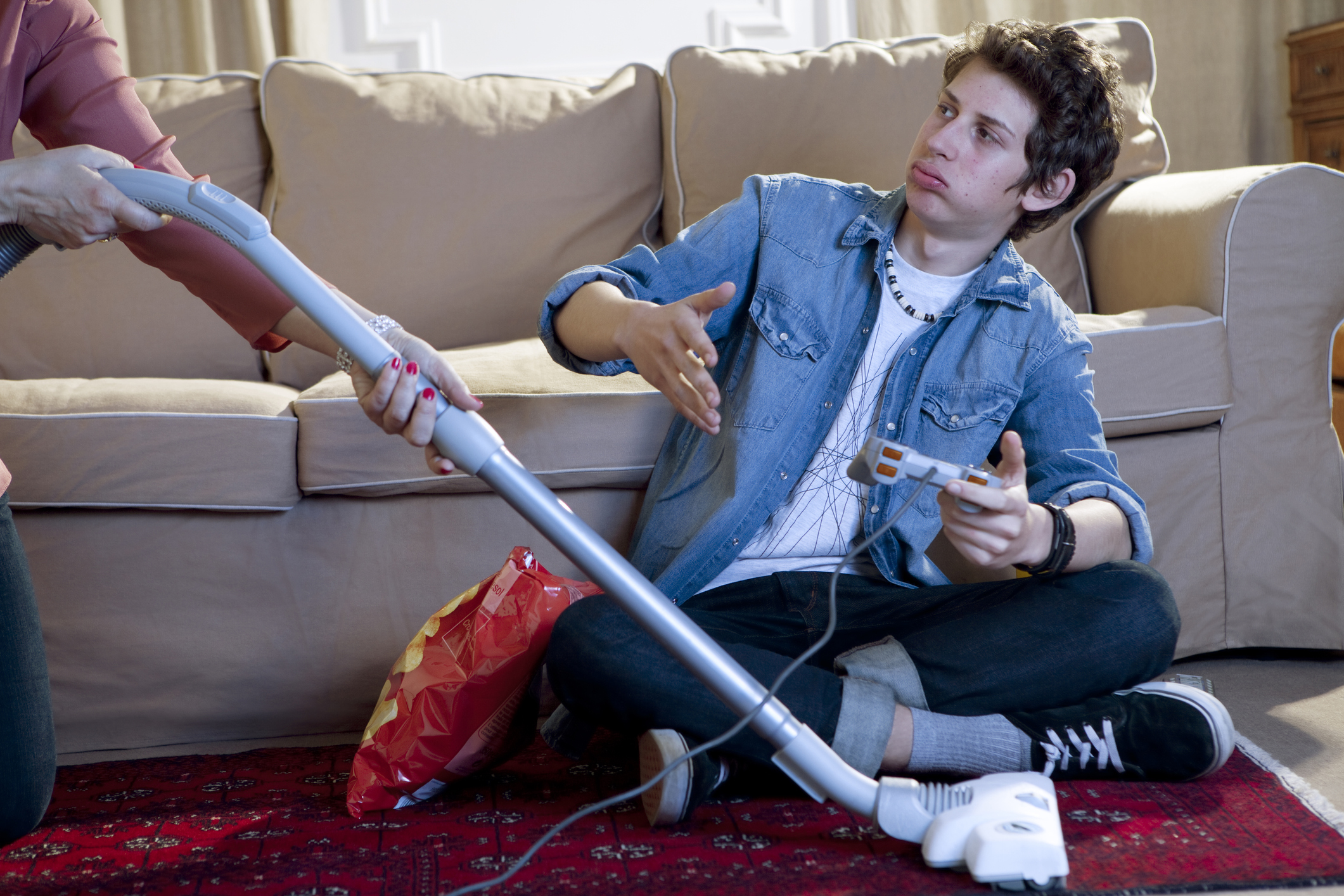 A woman vacuuming while a man plays a game | Source: Getty Images