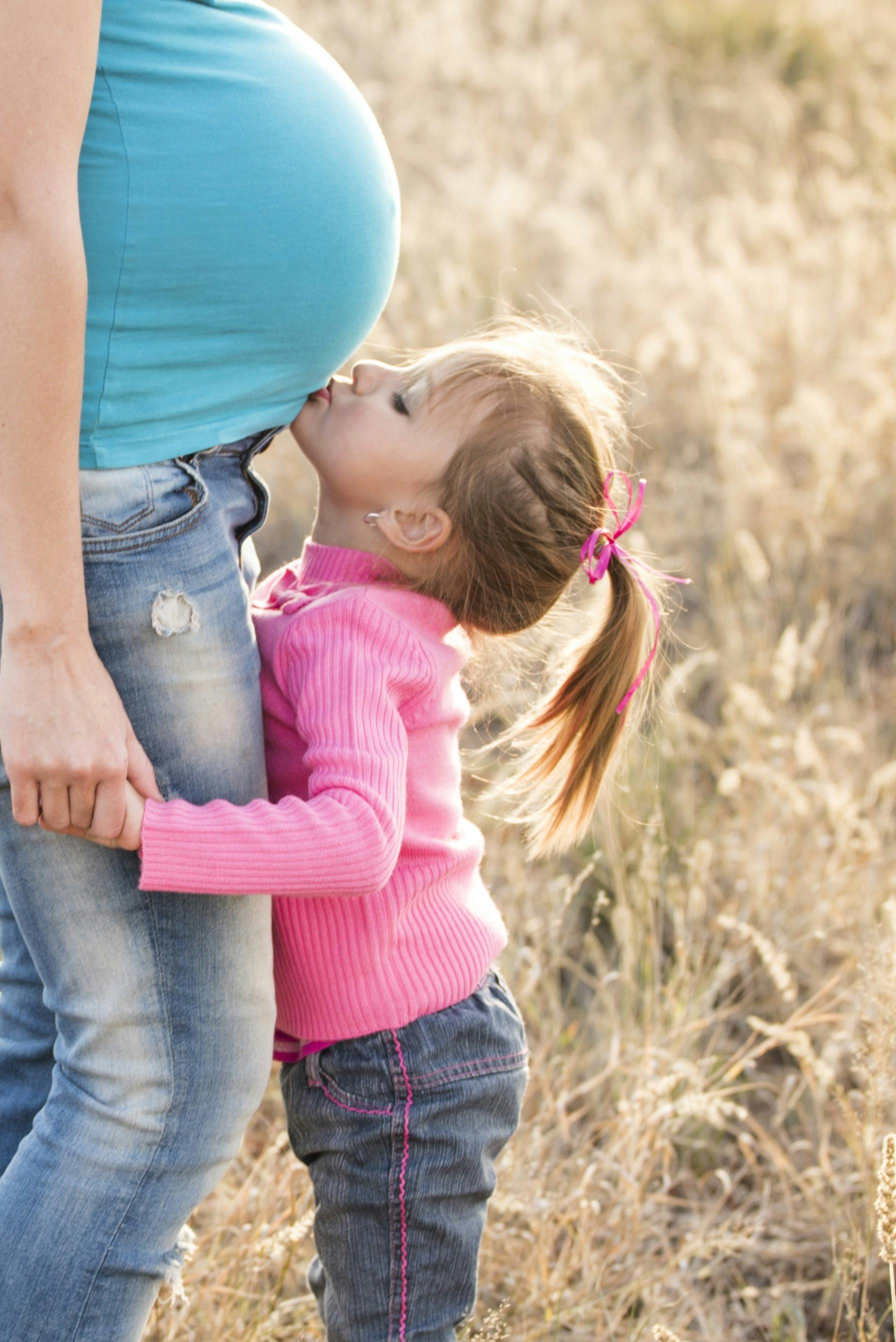 Niña besando un vientre embarazado | Fuente: Pexels