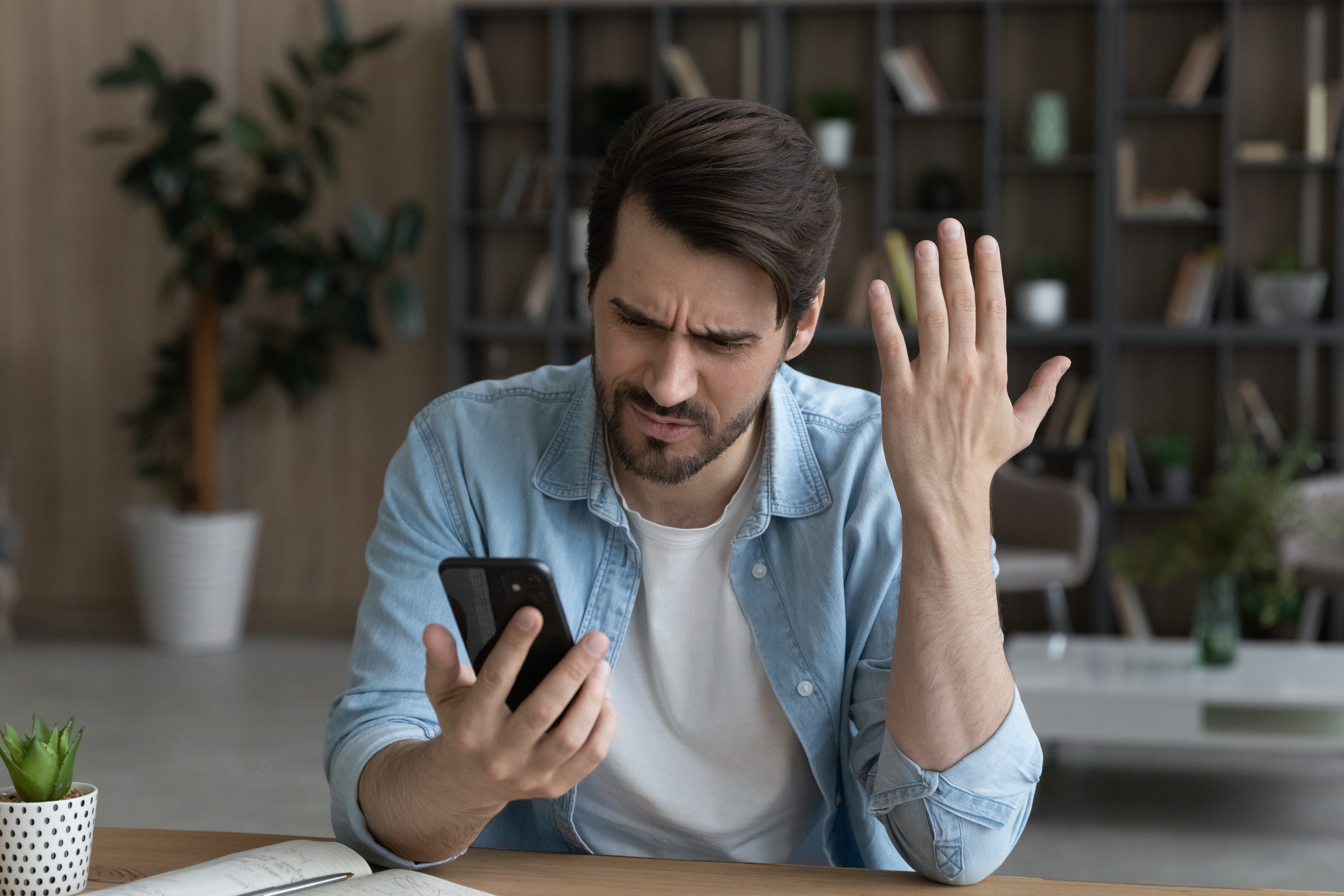 Ein Mann schaut wütend auf sein Telefon | Quelle: Shutterstock