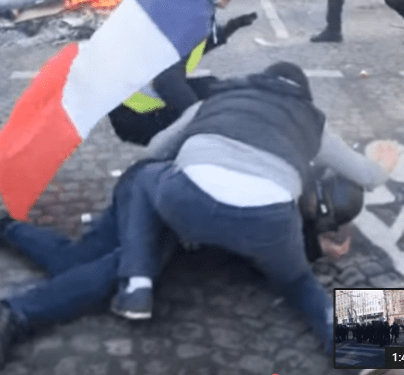 Adel et un Gilet jaune protégeant un policier sur les Champs-Elysées, le 16 mars 2019. | Photo : Youtube/InfoCritiqueWeb