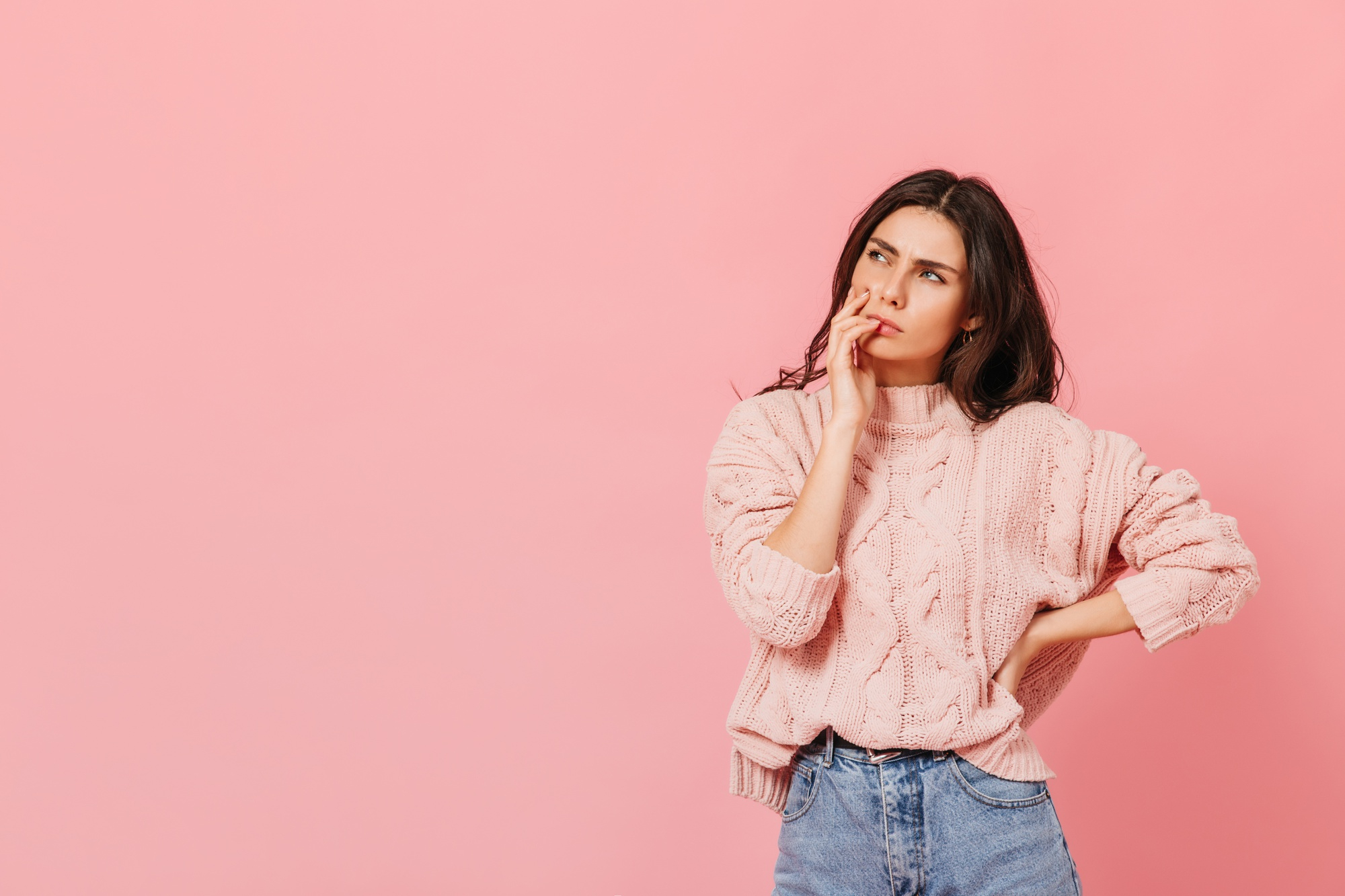 A woman in a pink sweater, thinking | Source: Freepik