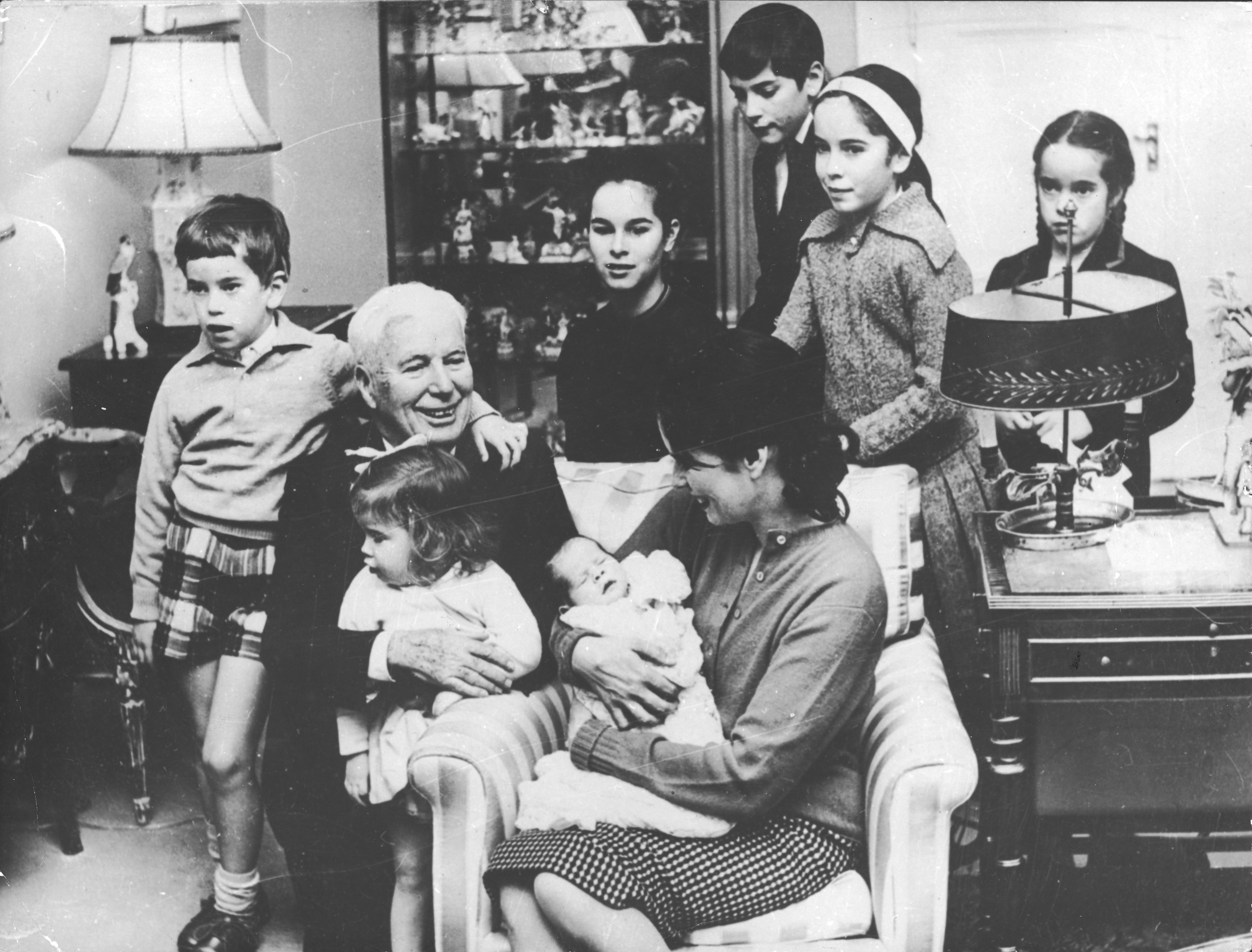 Charlie Chaplin with Jane on his lap, his wife Oona holding newborn Annette,  and their children, Eugene, Geraldine, Michael, Victoria, and Josephine at their home in Manoir de Ban, Switzerland, in December 1959 | Source: Getty Images