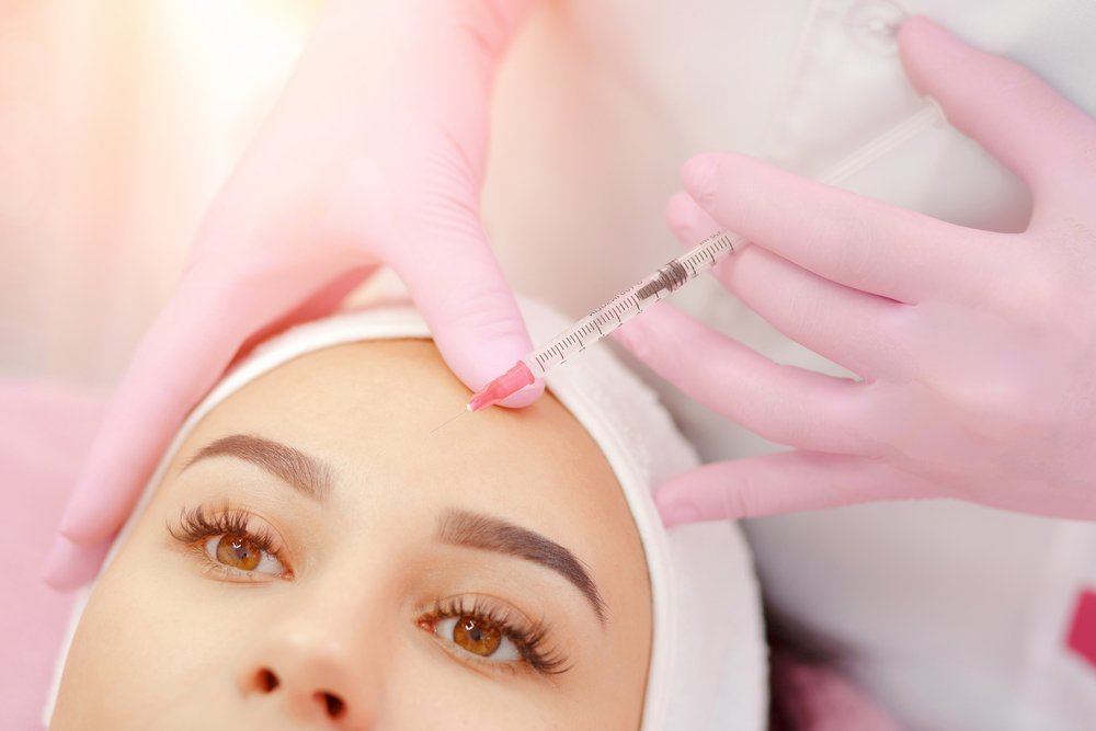 Mujer recostada recibiendo aplicación de bótox en la frente. | Foto: Shutterstock