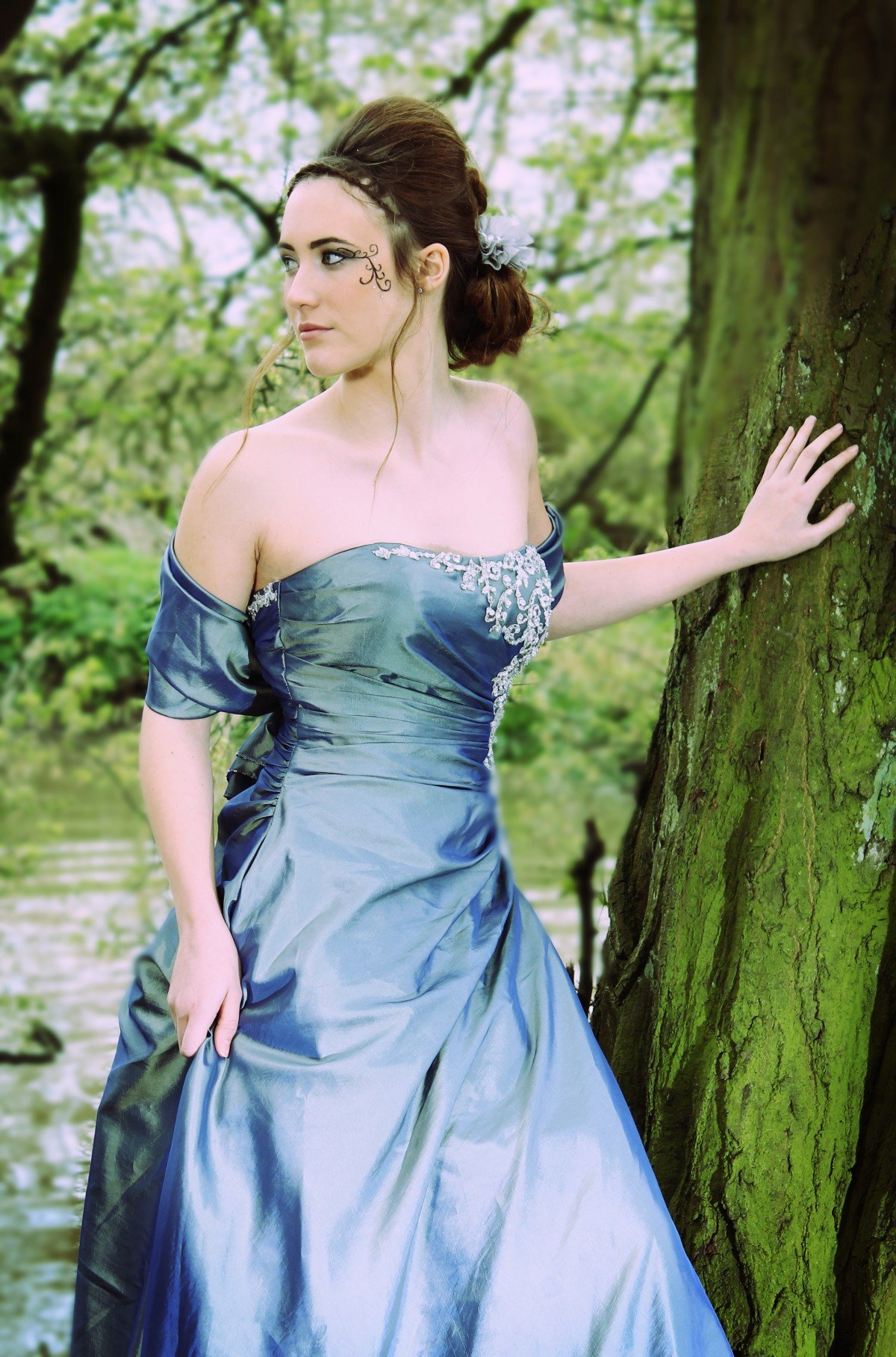 Mujer luciendo un vestido azul y un peinado alto, parada junto a un árbol frente al río. | Imagen: PxHere Mujer luciendo un vestido azul y un peinado alto, parada junto a un árbol frente al río. | Imagen: PxHere