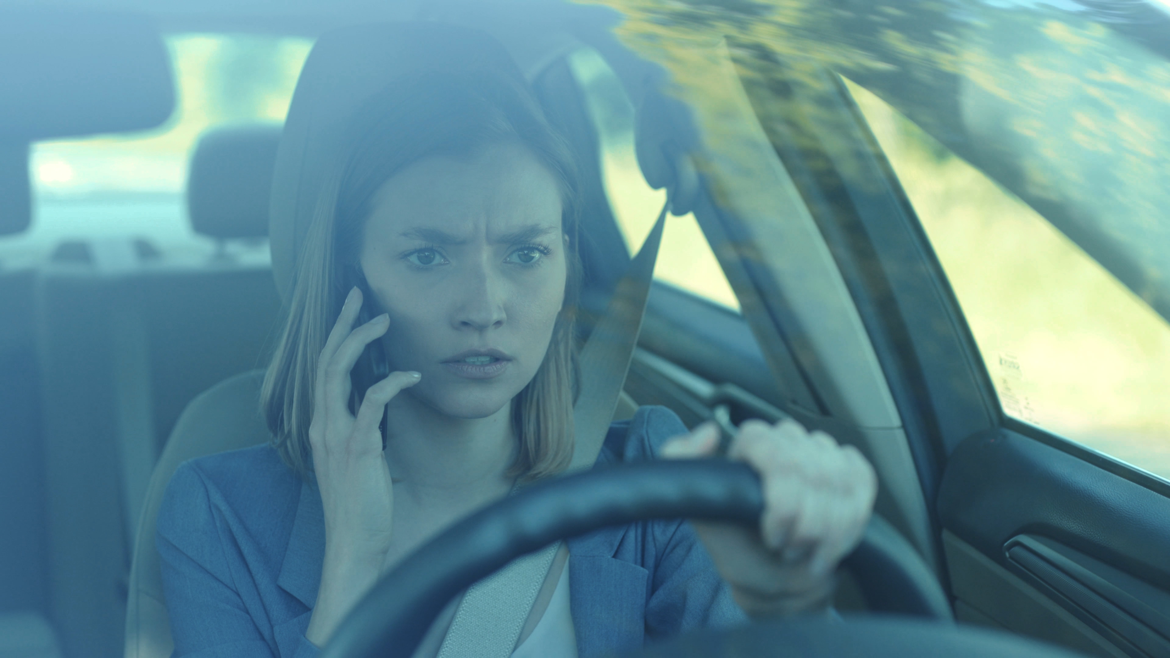 Sad young woman driver talking by phone while driving a car | Source: Shutterstock.com