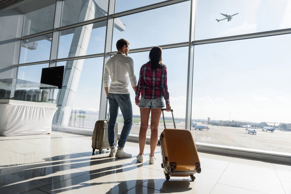 Pareja observando a través del ventanal de un aeropuerto. | Foto: Shutterstock