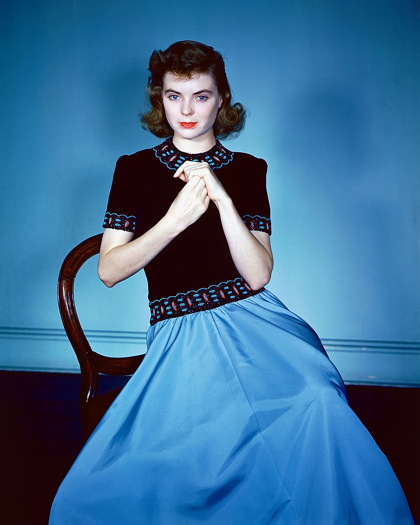 Dorothy McGuire (1916-2001) sitting on a chair, wearing a black top with red and blue trim and a blue skirt in a studio portrait, circa 1940. | Photo: Getty Images