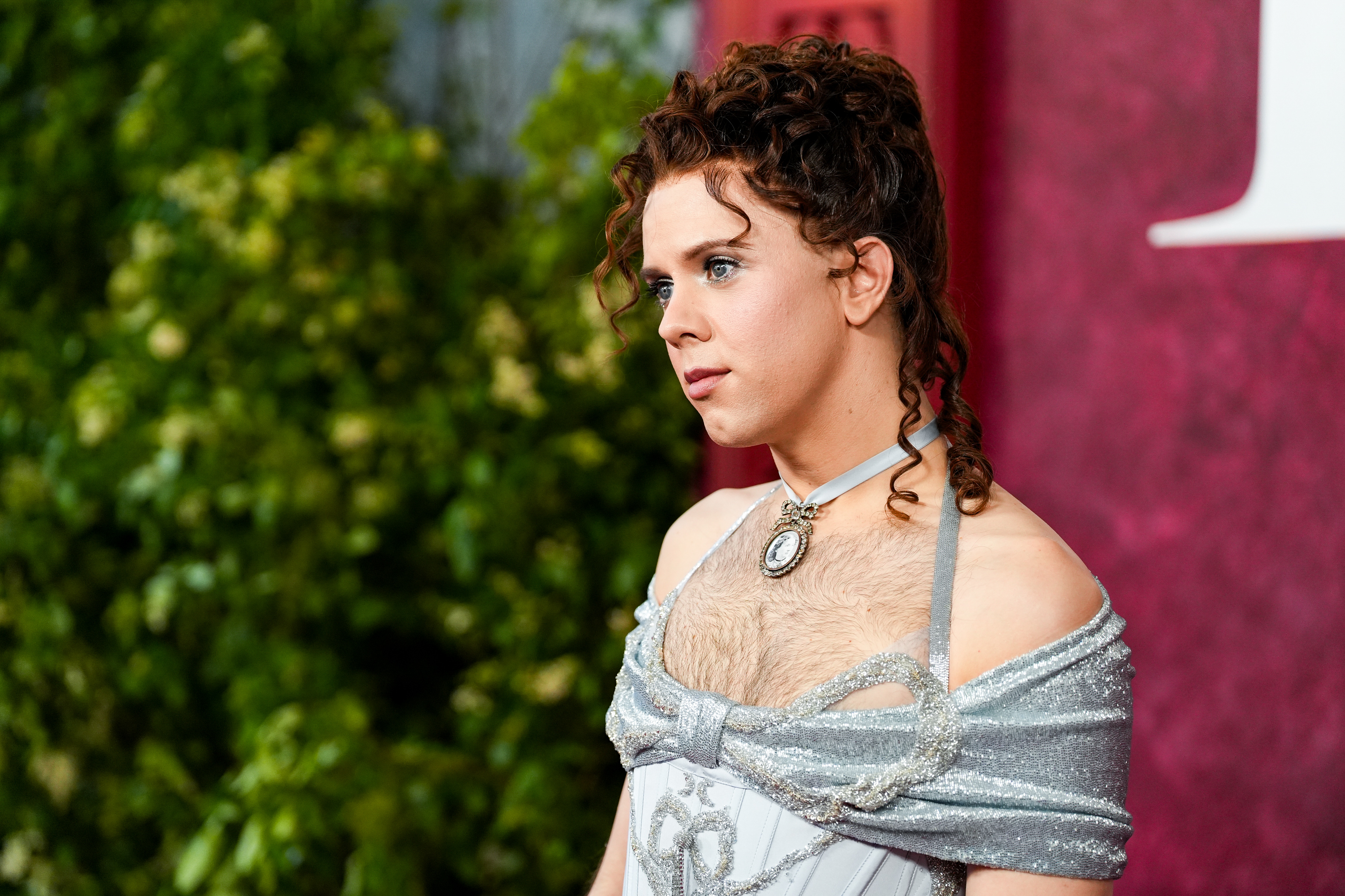 Cole Escola commands attention in a silver off-the-shoulder bodice, paired with softly styled curls and radiant makeup. Their fierce gaze and unique expression blend glam and confidence into a standout beauty and style moment on the red carpet.