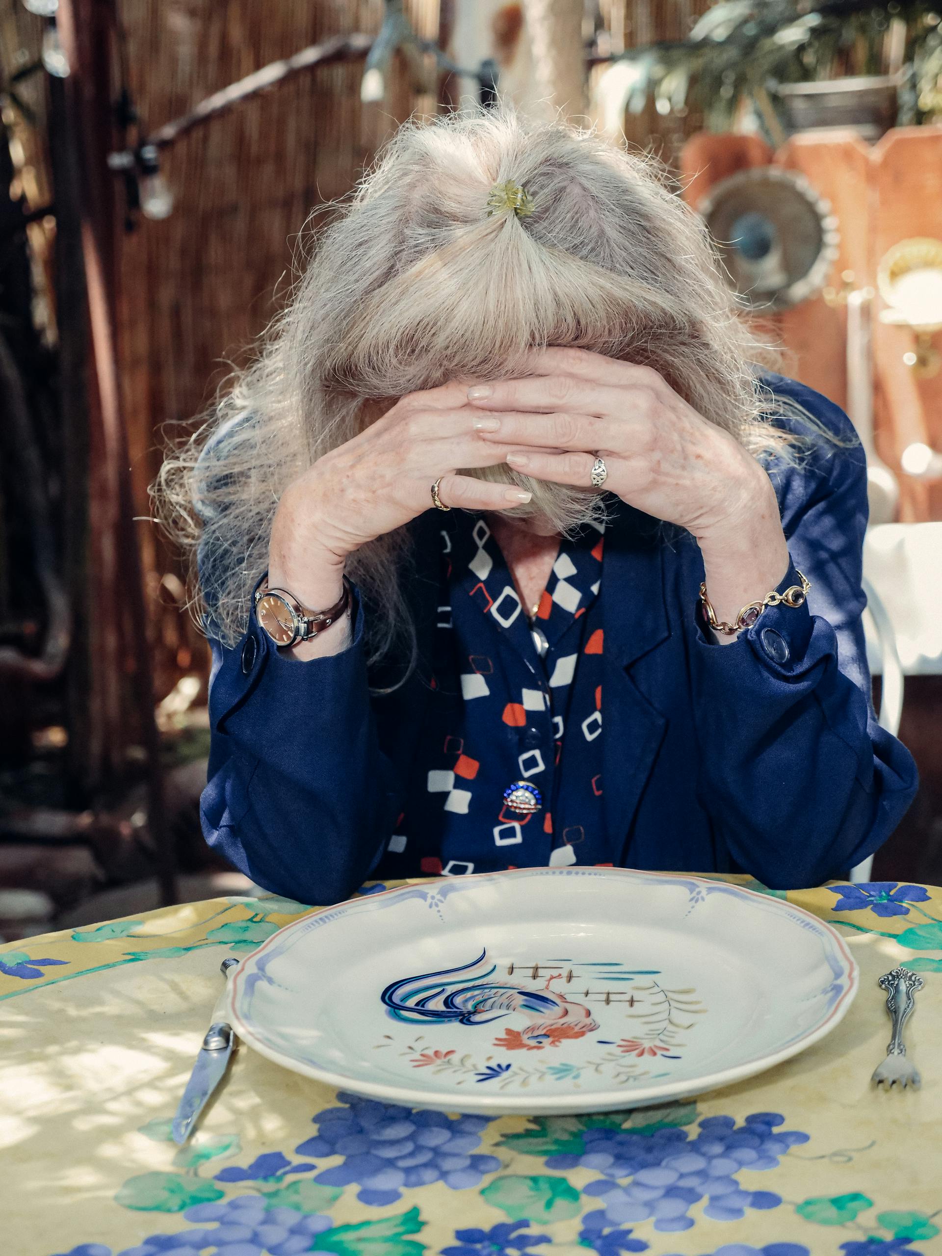 A sad older lady covering her face | Source: Pexels