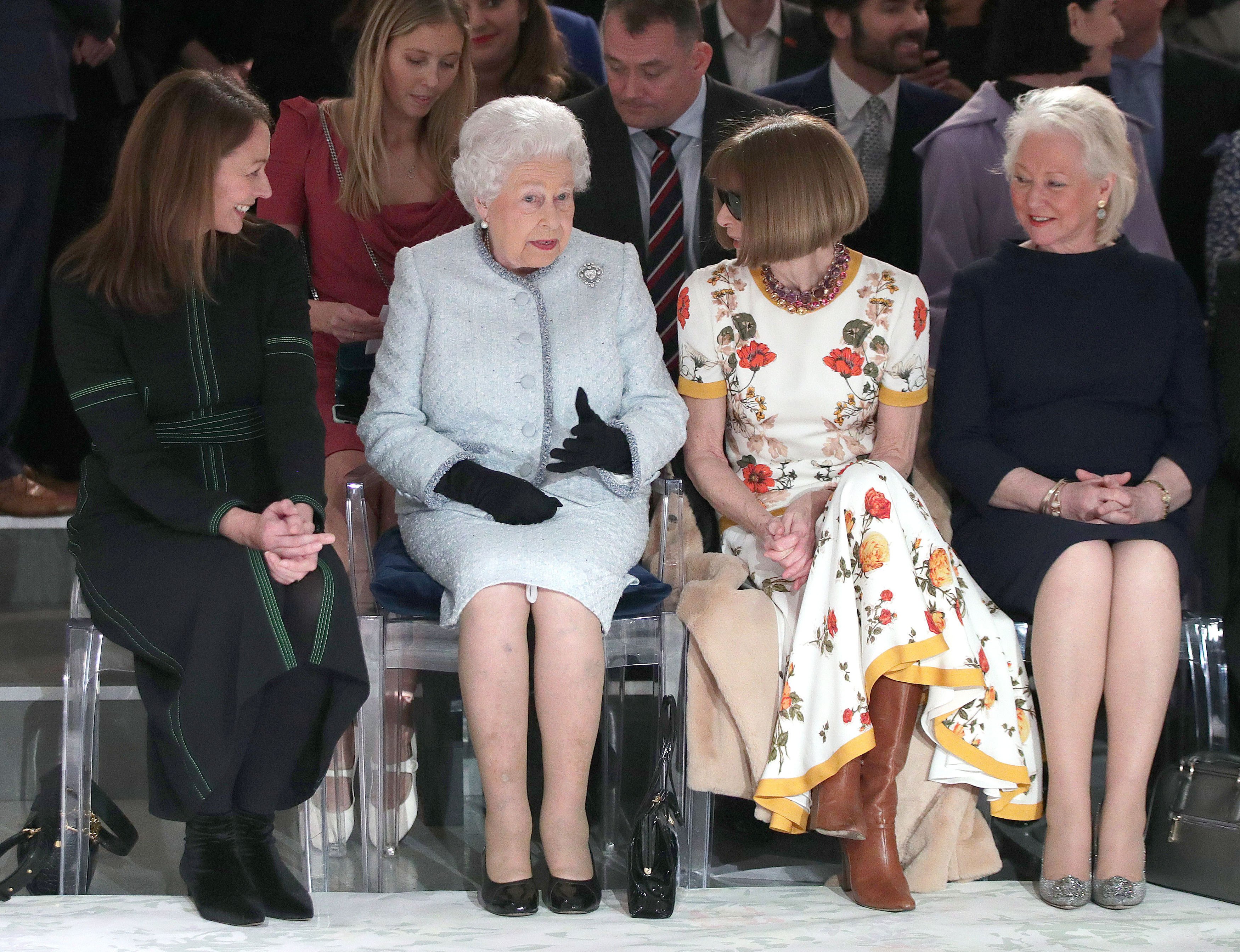 Queen Elizabeth II sitting with Anna Wintour, Caroline Rush (L), chief executive of the British Fashion Council (BFC) and royal dressmaker Angela Kelly (R) as they view Richard Quinn's runway show during London Fashion Week's BFC Show Space on February 20, 2018 in London, United Kingdom | Source: Getty Images