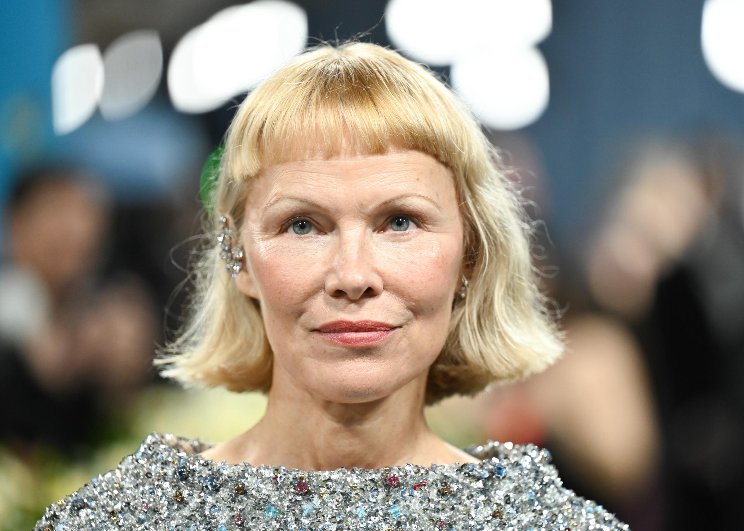 A close-up of Pamela Anderson showcases her makeup-free face, cropped bangs, and crystal-detailed dress. Her strikingly pared-back look was a standout at the Met Gala celebrating "Superfine: Tailoring Black Style" at the Metropolitan Museum of Art.