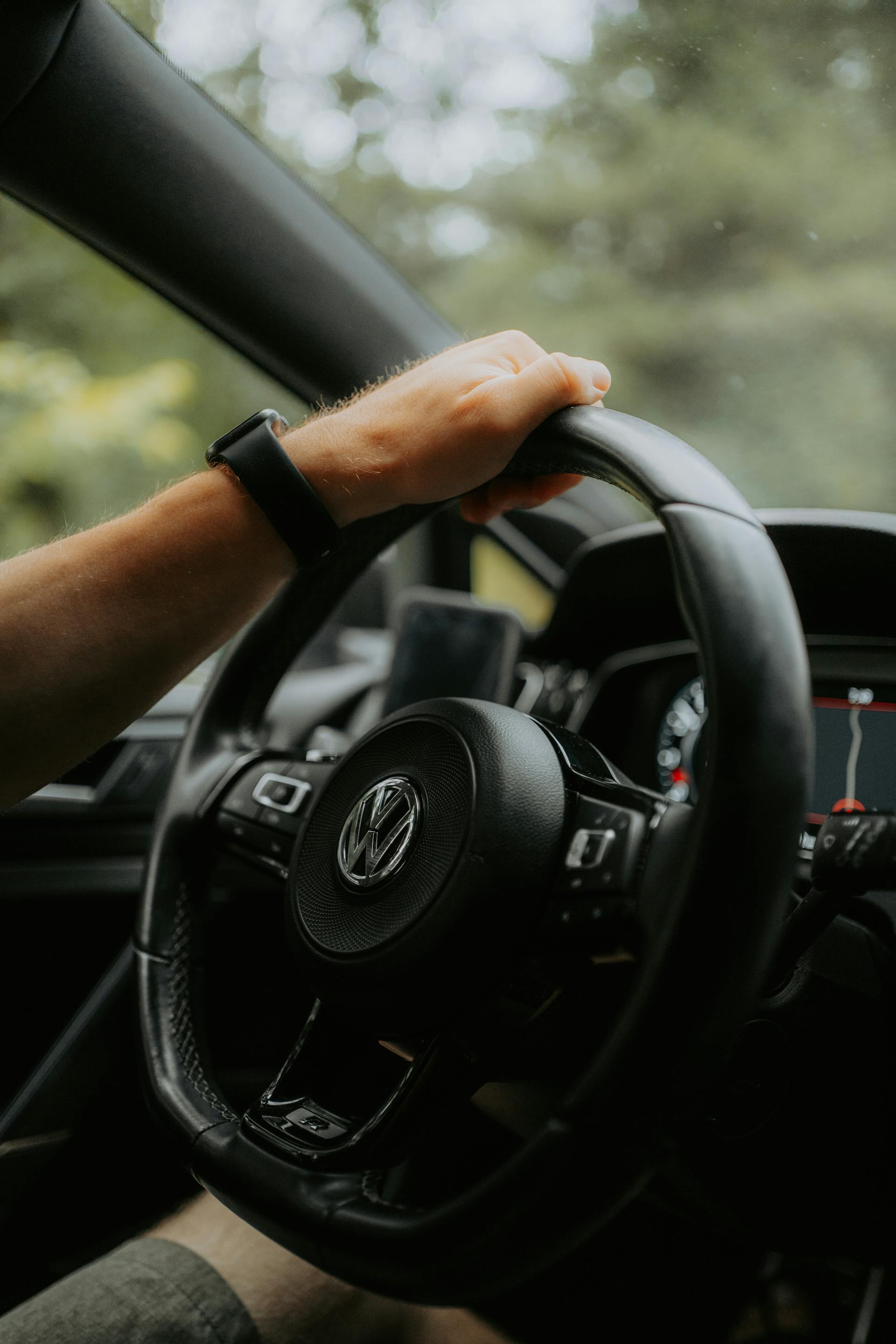 A man holding the steering wheel of a Volkswagen car with one hand | Source: Pexels