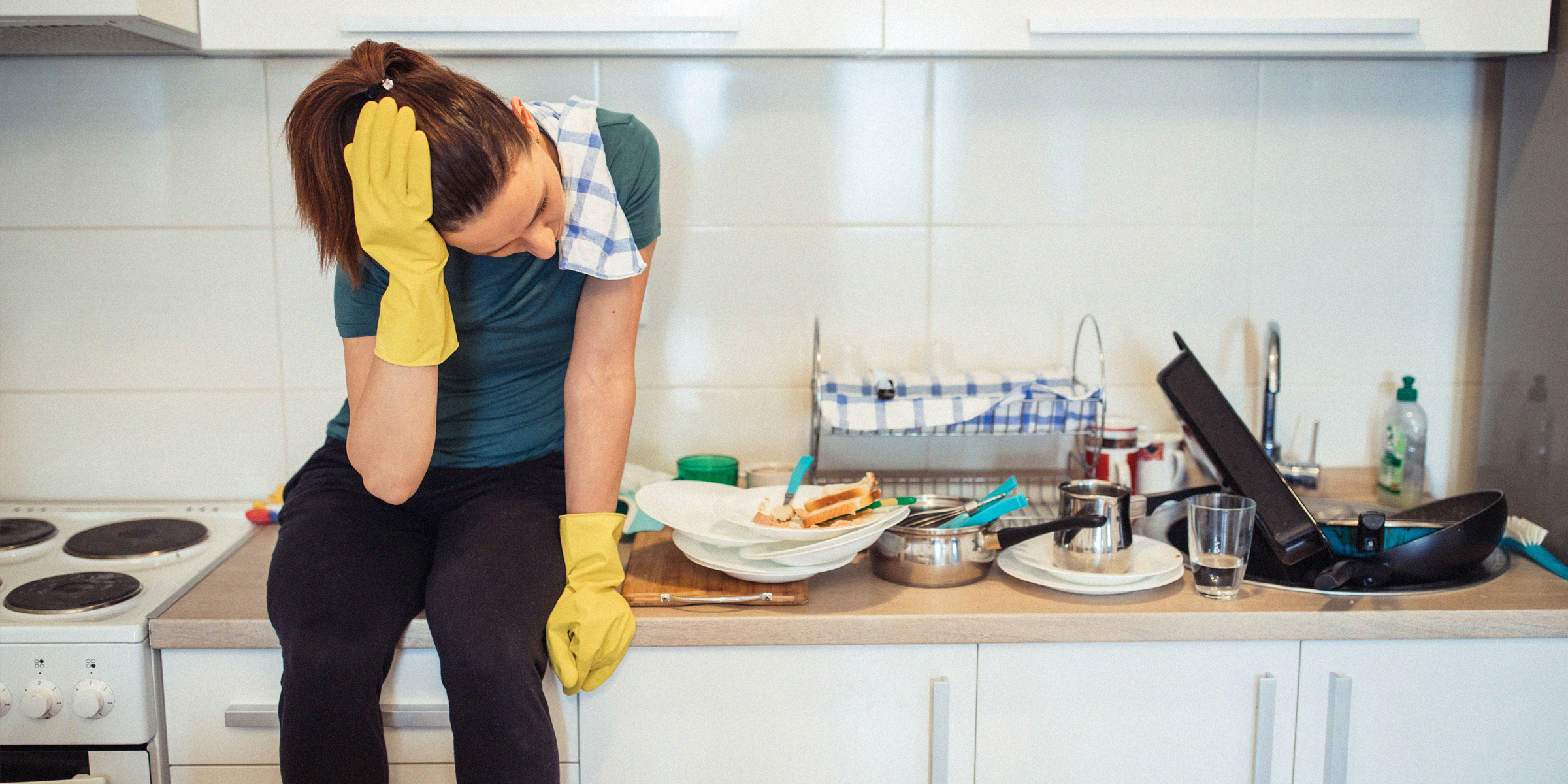 A tired mom next to a kitchen sink full of dishes | Source: Getty Images