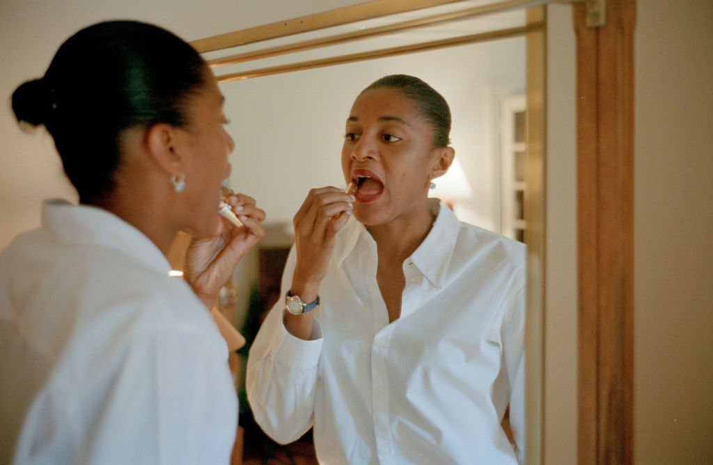 Une femme en train de mettre du rouge à lèvres. ǀ Source : Getty Images