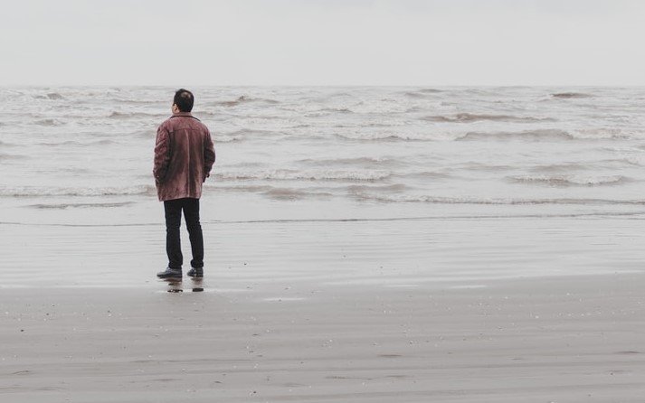 Man standing alone on a beach | Source: Unsplash