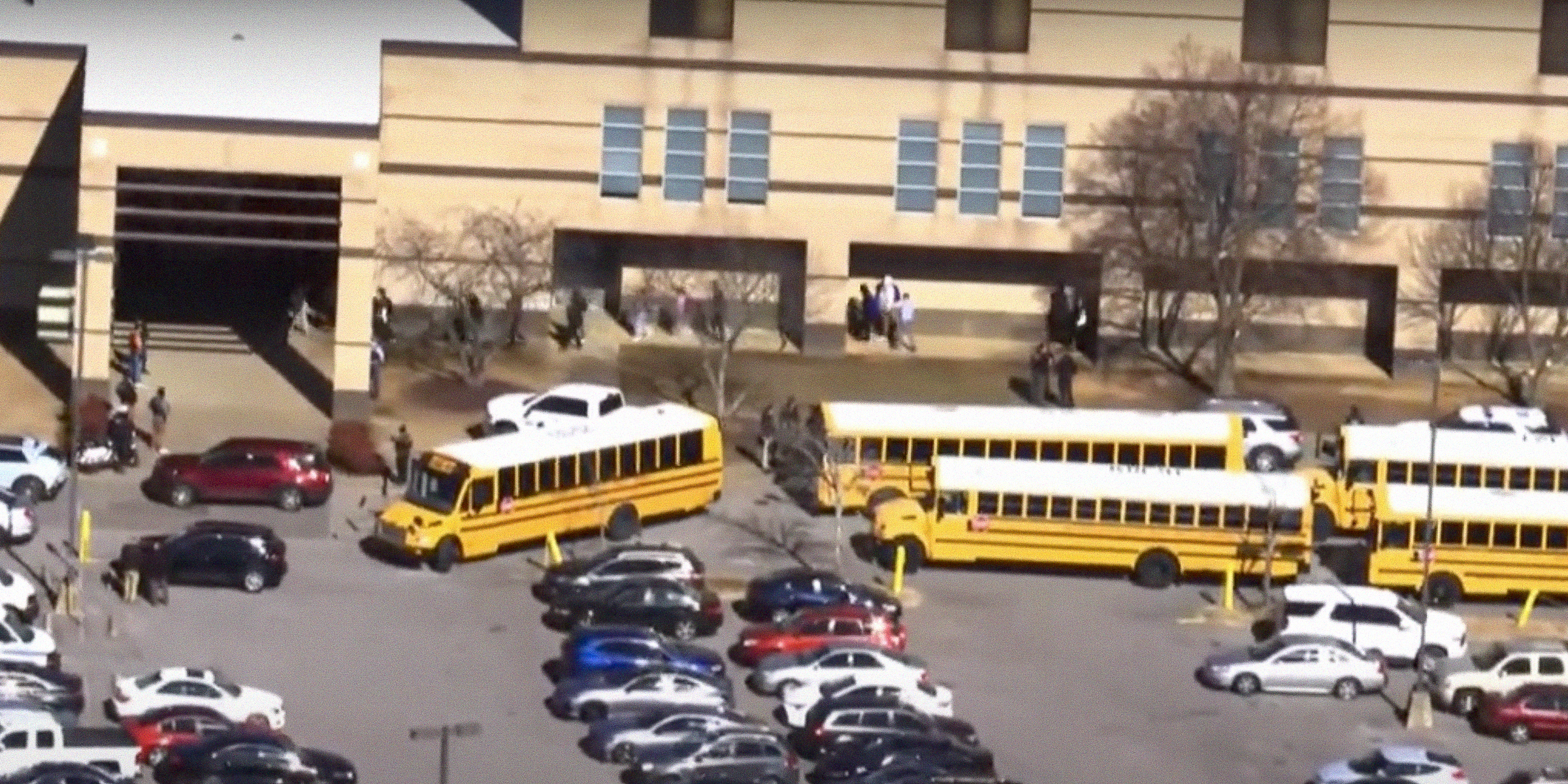 School buses and cars parked outside of a school. | Source: YouTube/WVLTTV